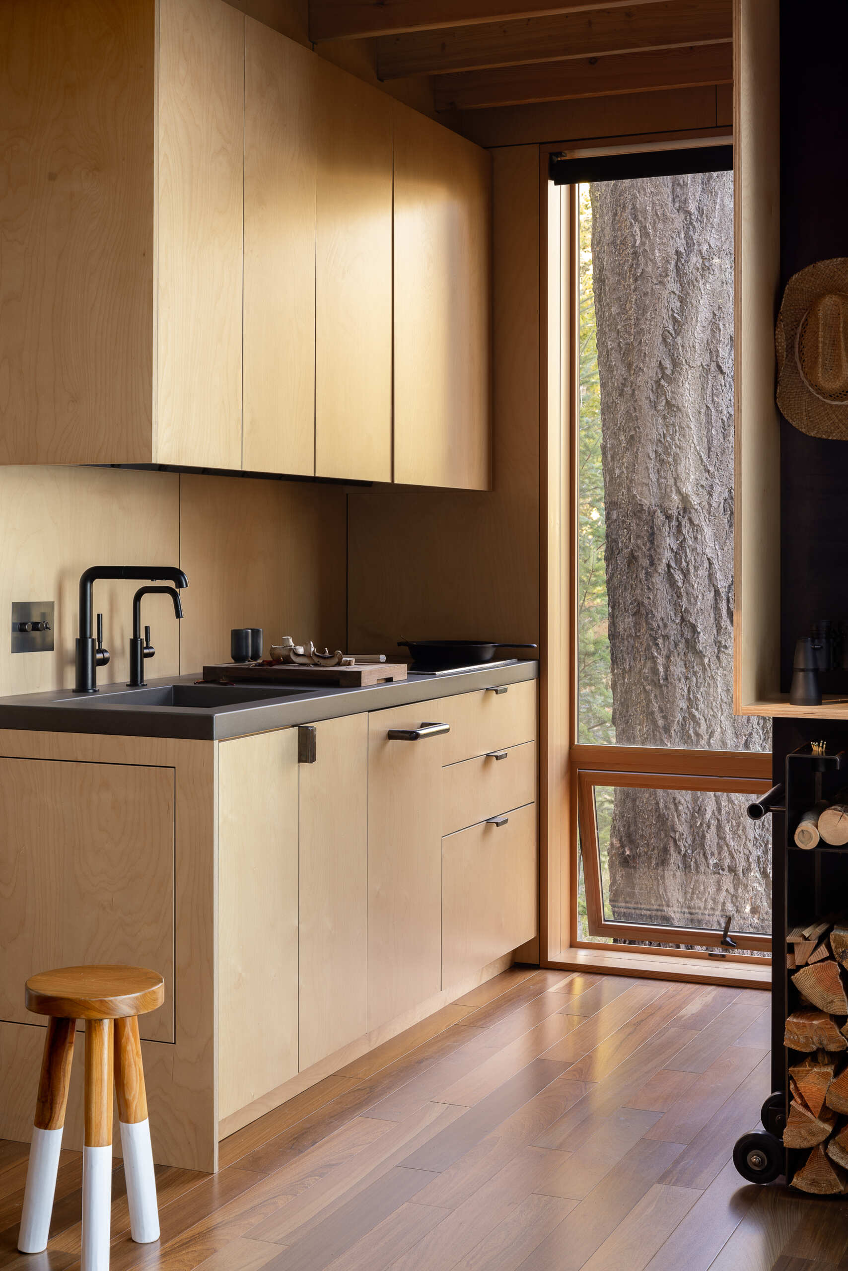 See how a compact kitchen tucked beneath the loft makes smart use of space with concrete countertops, a ceramic cooktop, matte black faucet and undercounter appliances.