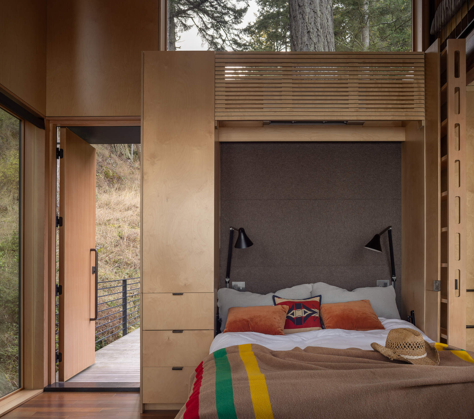This tiny cabin's Murphy bed folds away to preserve the open studio layout, while an east-facing position welcomes morning sunlight into the sleeping area.