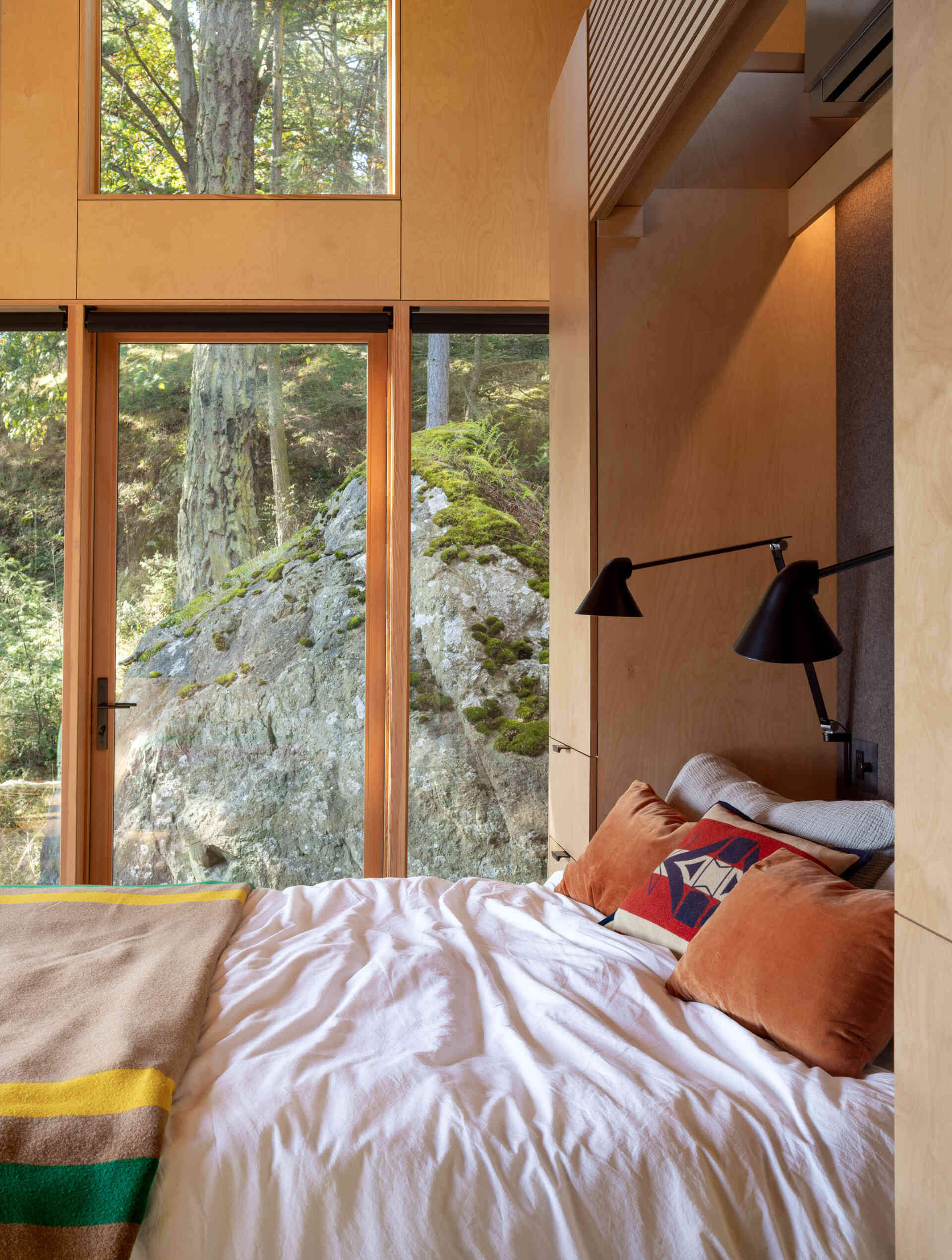 This tiny cabin's Murphy bed folds away to preserve the open studio layout, while an east-facing position welcomes morning sunlight into the sleeping area.