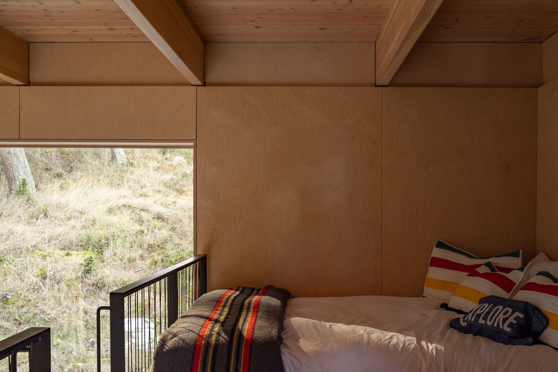 A custom maple ladder leads to a compact loft with two bunks above the kitchen, adding sleeping space without increasing the 400-square-foot cabin's footprint.
