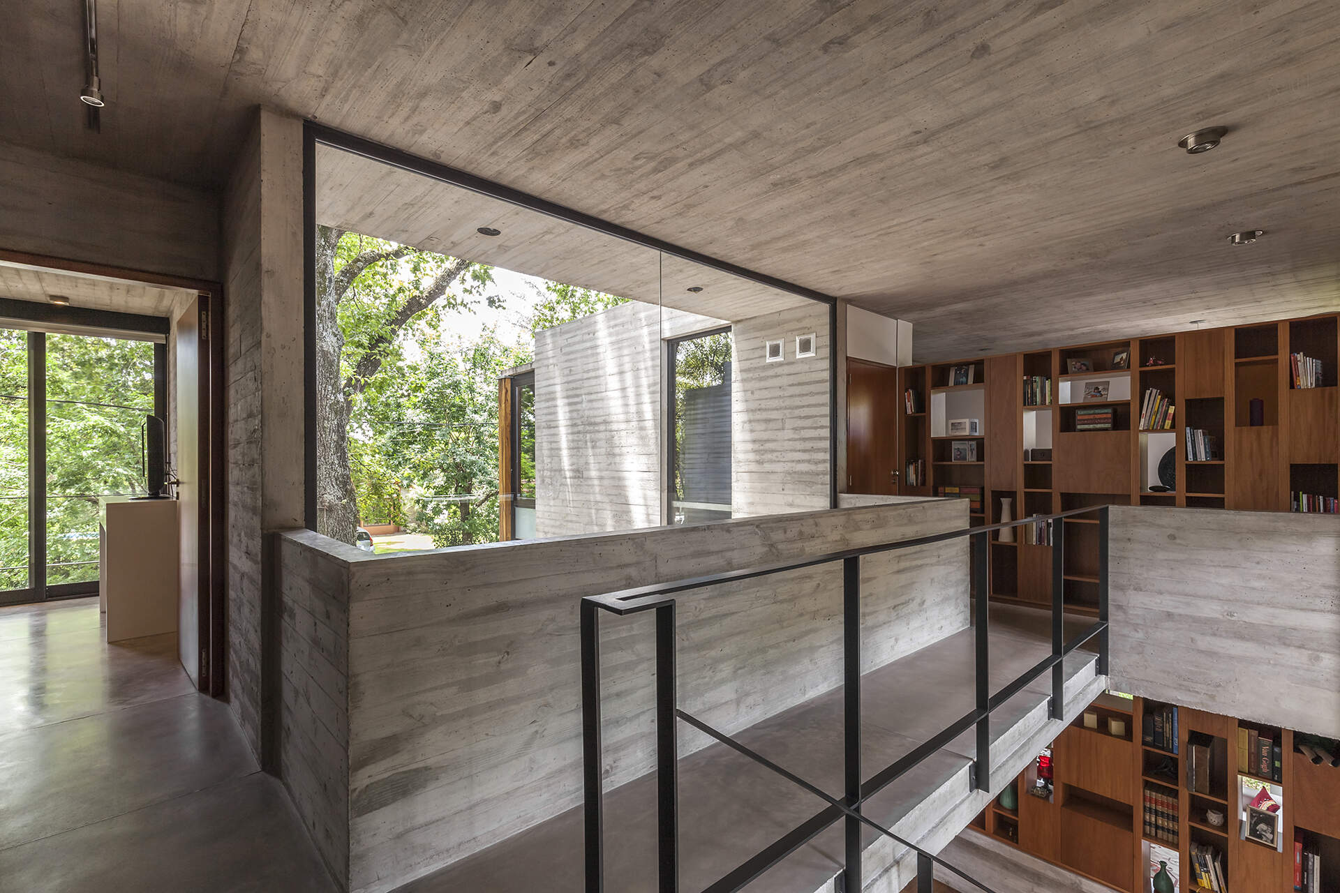 A small bridge and wood cabinetry continue the timber details found downstairs, creating a visual connection between the different levels of this modern Buenos Aires home.