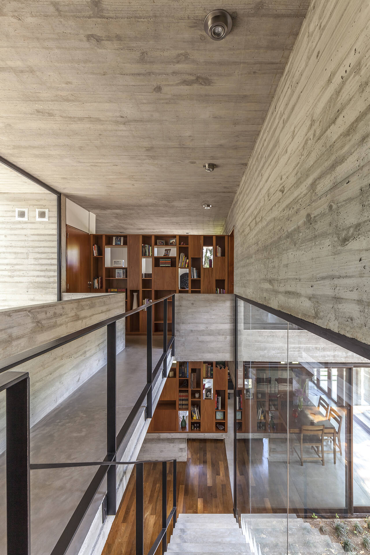 A small bridge and wood cabinetry continue the timber details found downstairs, creating a visual connection between the different levels of this modern Buenos Aires home.