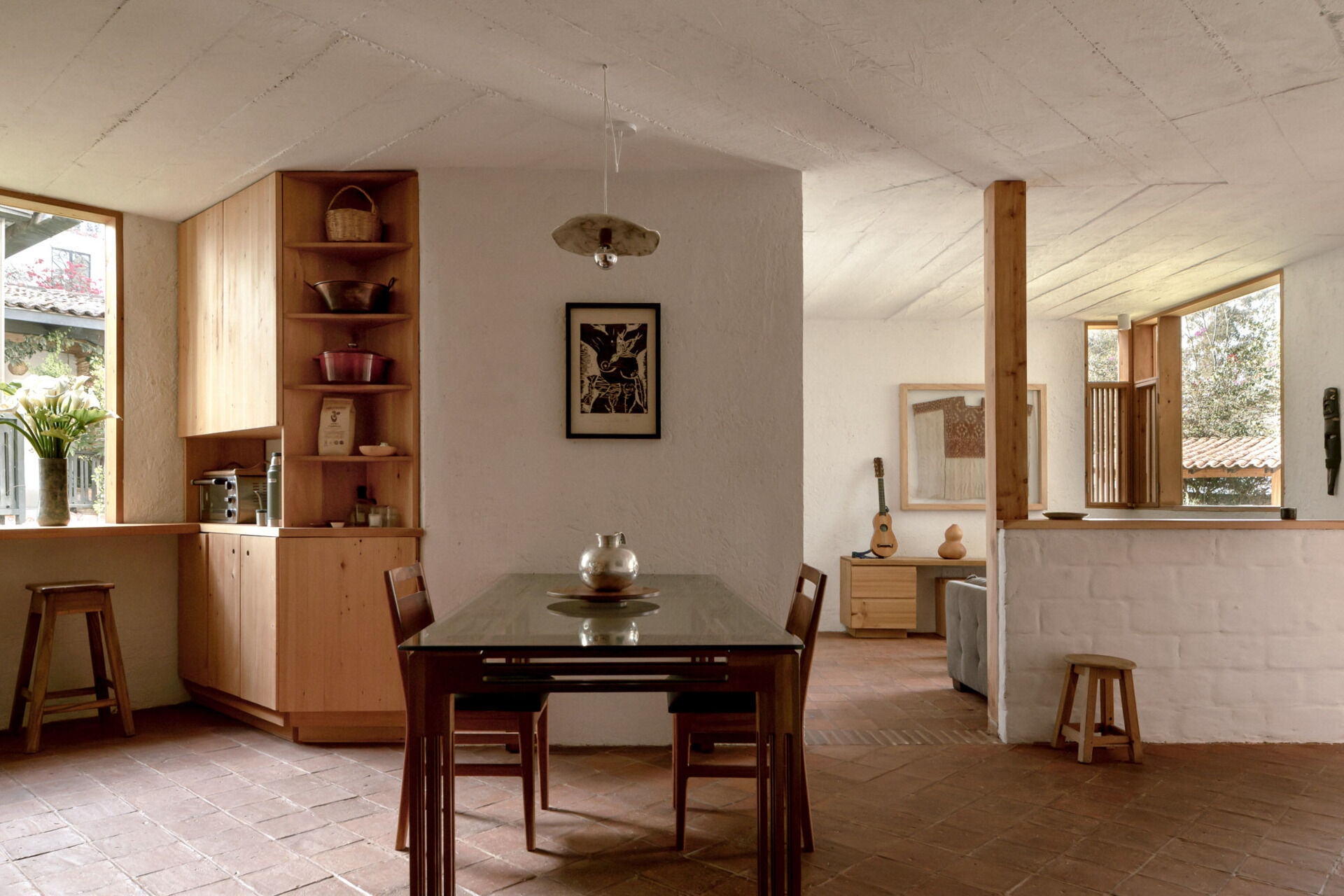 Explore Casa Amona’s open dining room and kitchen, with cypress cabinetry, clay tile floors and windows that frame planting just beyond the counters.