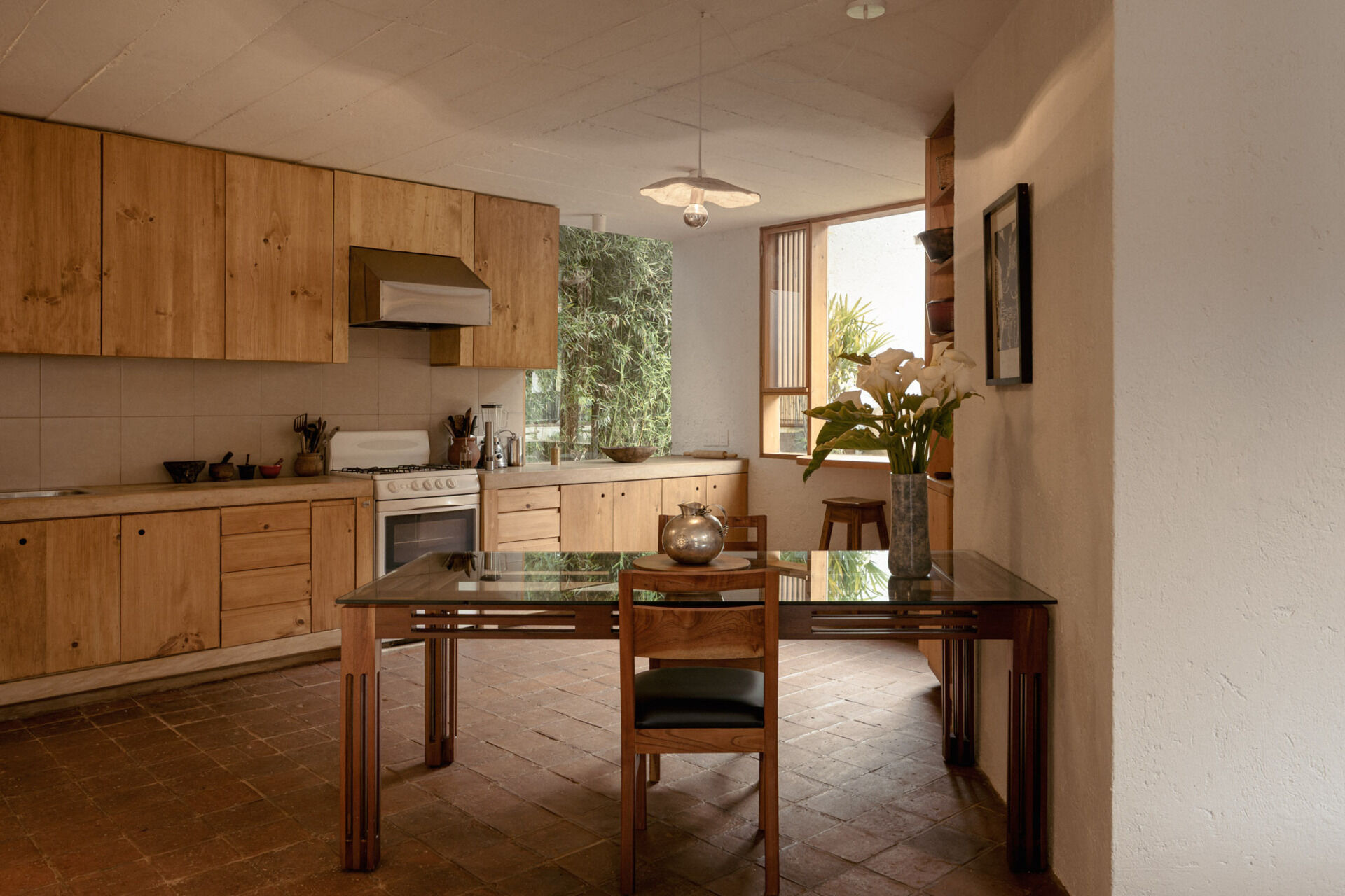 Explore Casa Amona’s open dining room and kitchen, with cypress cabinetry, clay tile floors and windows that frame planting just beyond the counters.