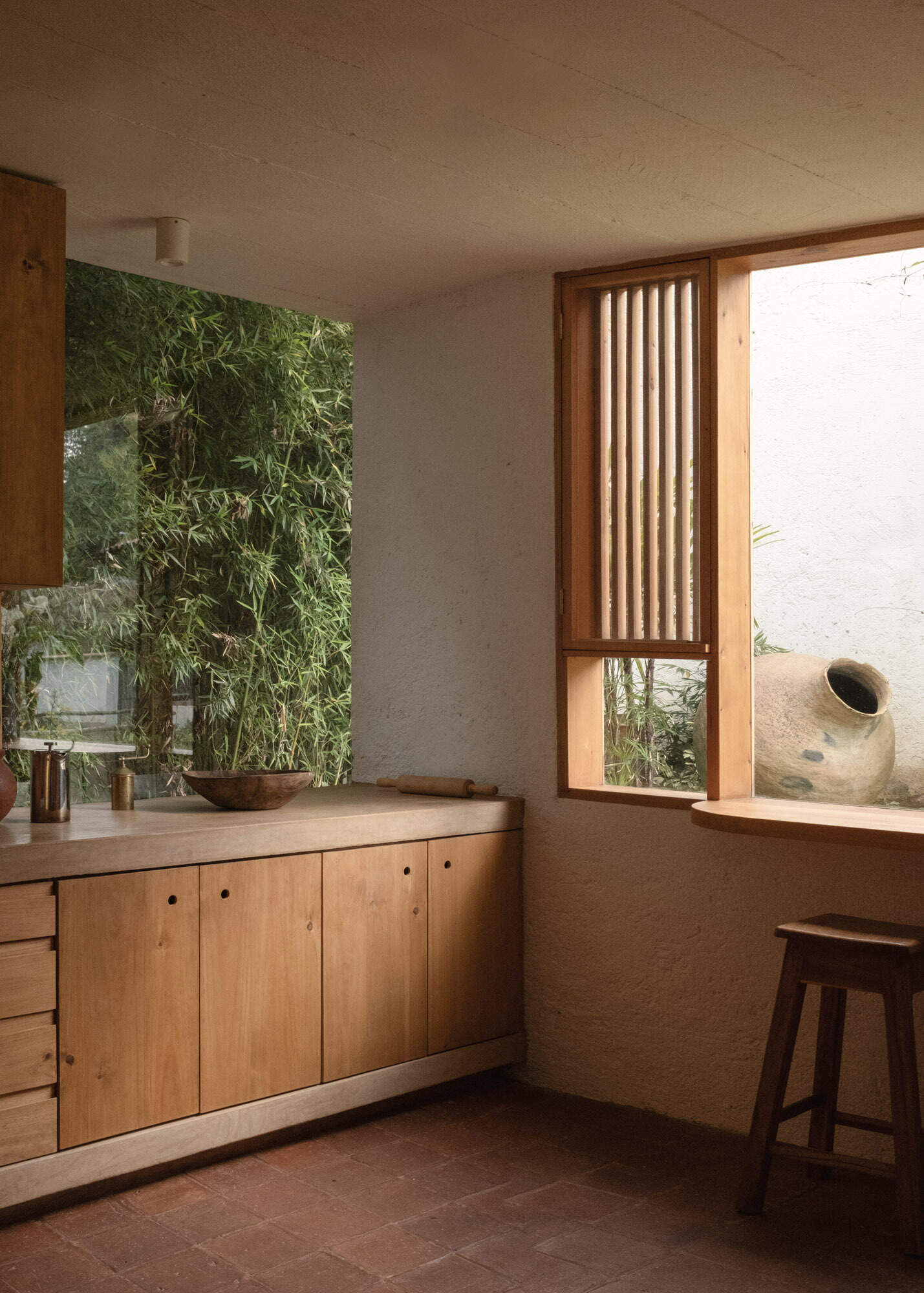Explore Casa Amona’s open dining room and kitchen, with cypress cabinetry, clay tile floors and windows that frame planting just beyond the counters.