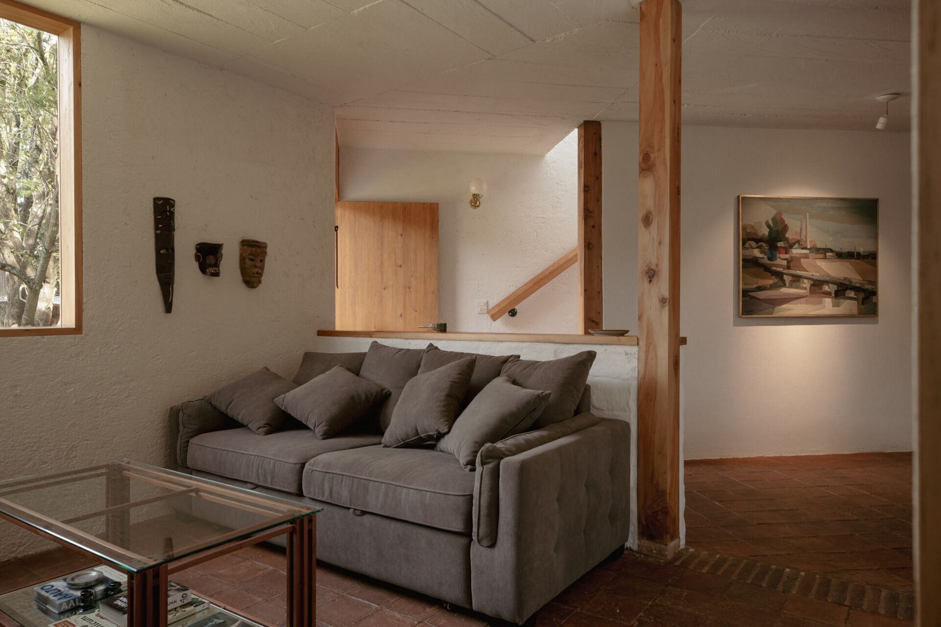 See inside Casa Amona’s living room, where clay tile floors, timber details and a corner window create a warm, compact space designed to adapt over time.