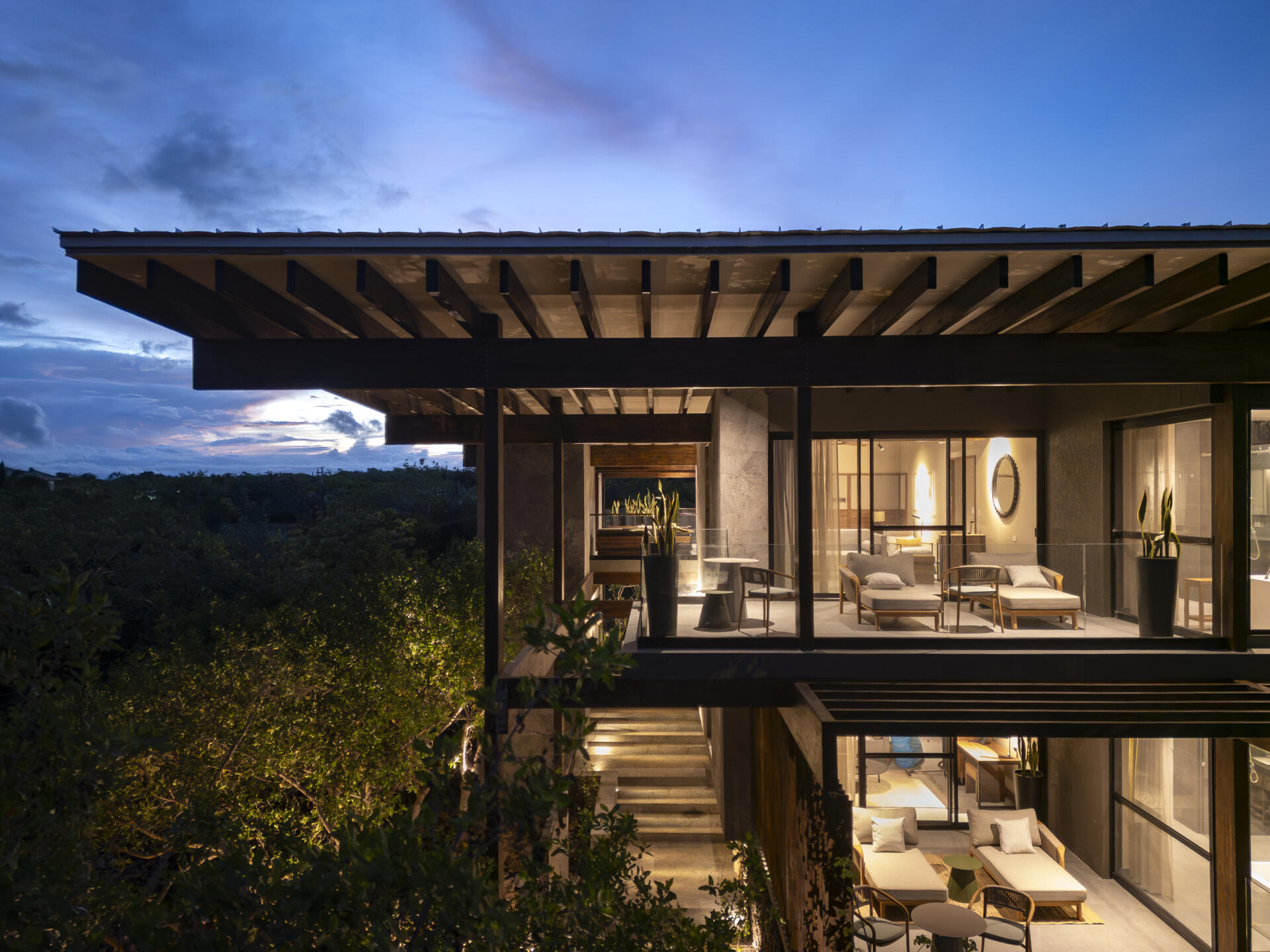 Explore the Finch Bay Galápagos Hotel expansion near Puerto Ayora, Ecuador, by Alfredo Ribadeneira Arquitectos. Prefabricated teak construction, deep roof overhangs, glass-fronted terraces, and neutral guest spaces frame views of trees and volcanic rock.