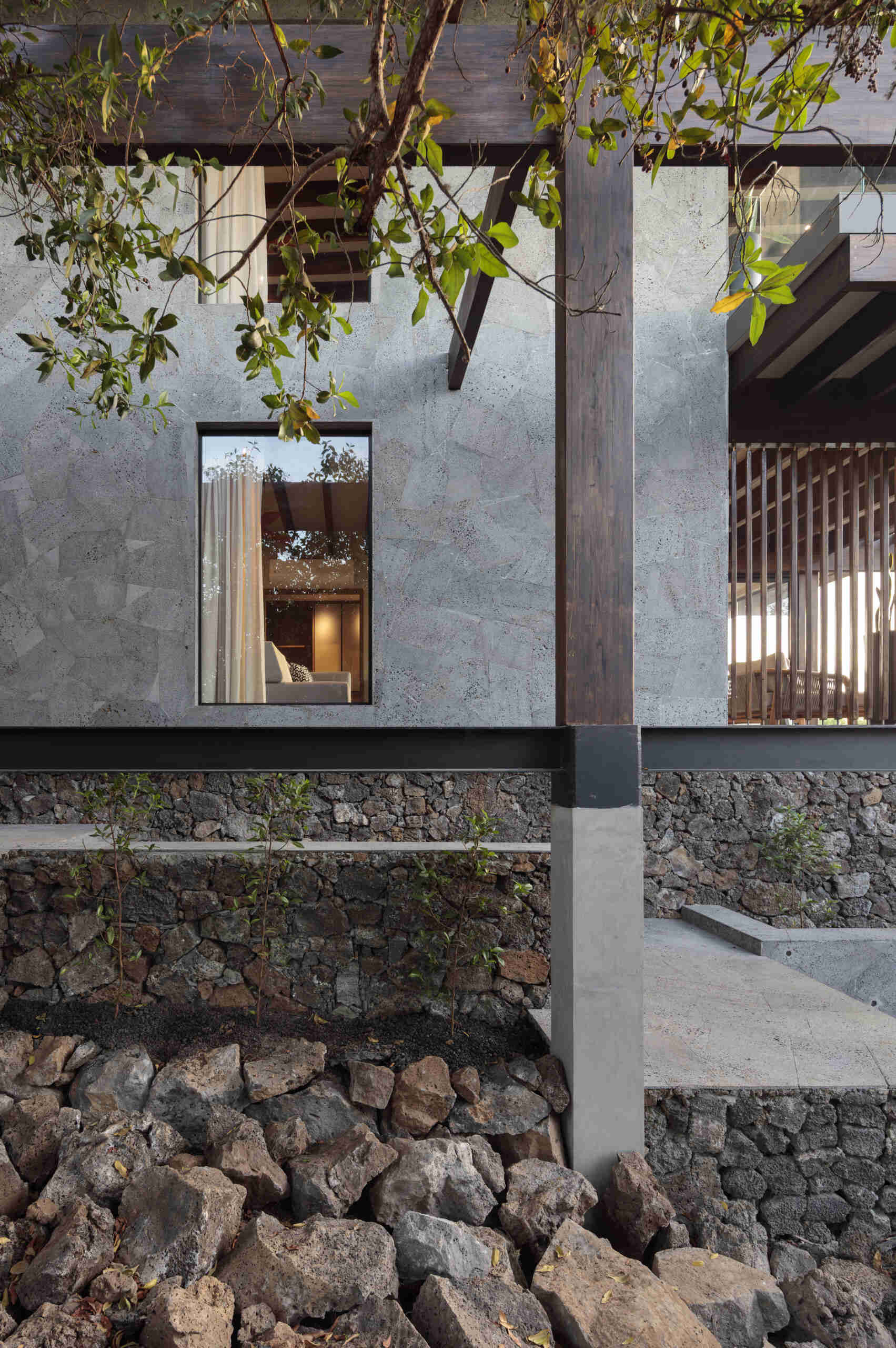 Explore the Finch Bay Galápagos Hotel expansion near Puerto Ayora, Ecuador, by Alfredo Ribadeneira Arquitectos. Prefabricated teak construction, deep roof overhangs, glass-fronted terraces, and neutral guest spaces frame views of trees and volcanic rock.