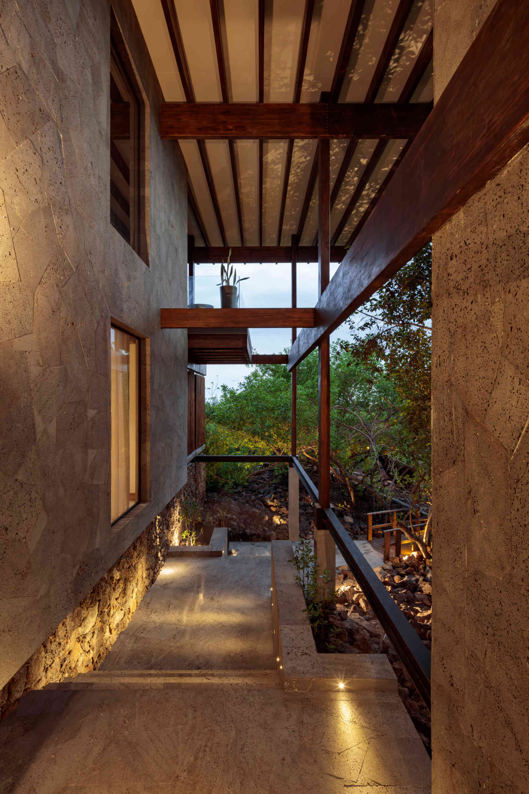 Explore the Finch Bay Galápagos Hotel expansion near Puerto Ayora, Ecuador, by Alfredo Ribadeneira Arquitectos. Prefabricated teak construction, deep roof overhangs, glass-fronted terraces, and neutral guest spaces frame views of trees and volcanic rock.