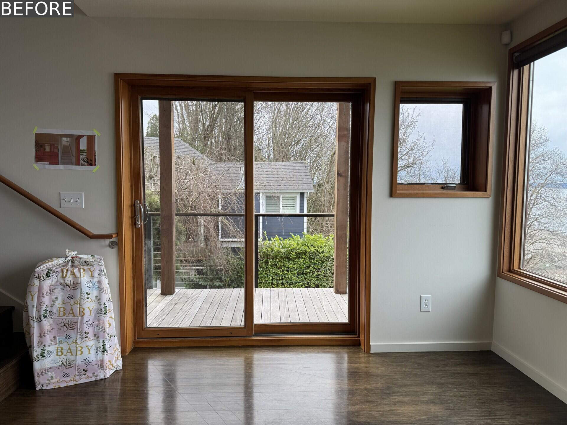 See the living room before renovation, with white walls, dark floors, timber-framed windows and an incredible Puget Sound view that had yet to become a bigger part of the room itself.