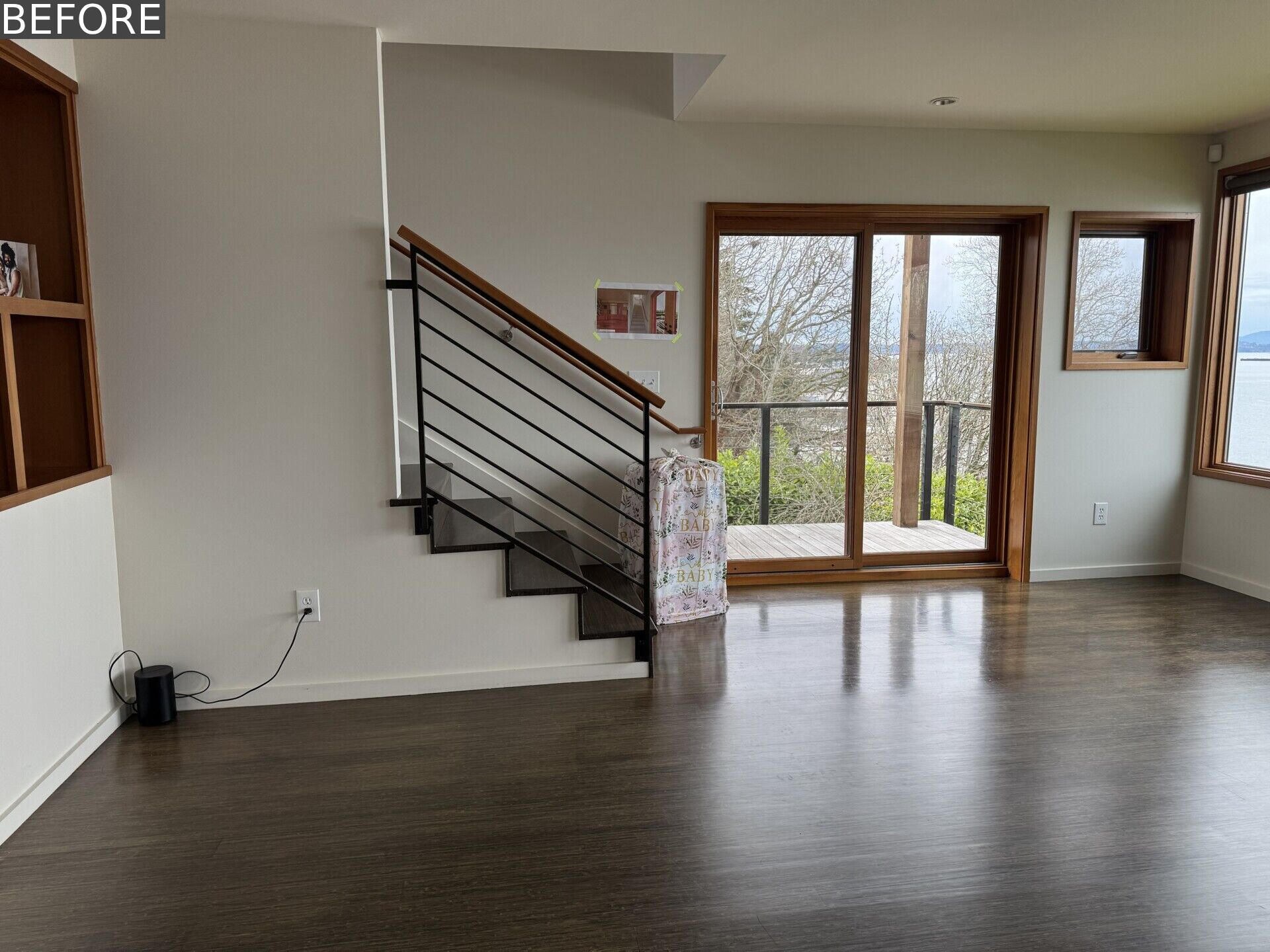 See the living room before renovation, with white walls, dark floors, timber-framed windows and an incredible Puget Sound view that had yet to become a bigger part of the room itself.