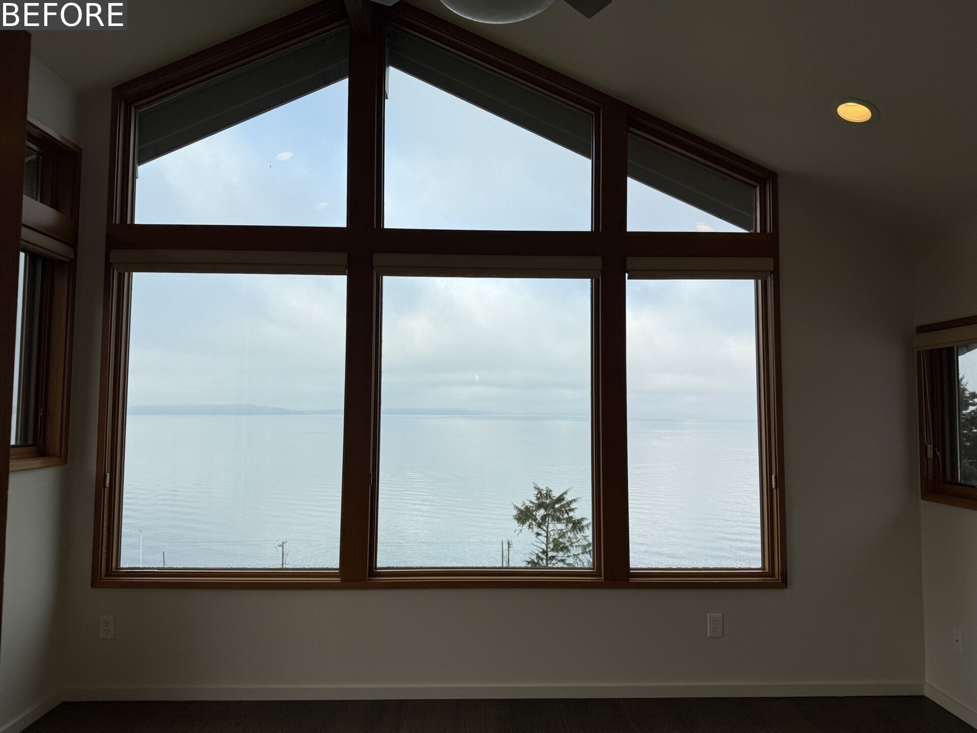 Tour the primary bedroom at Alki Lookout, where SHED paired existing panoramic Puget Sound windows with pale timber built-ins, a custom bed platform, concealed drawers and a pink-cushioned window bench.