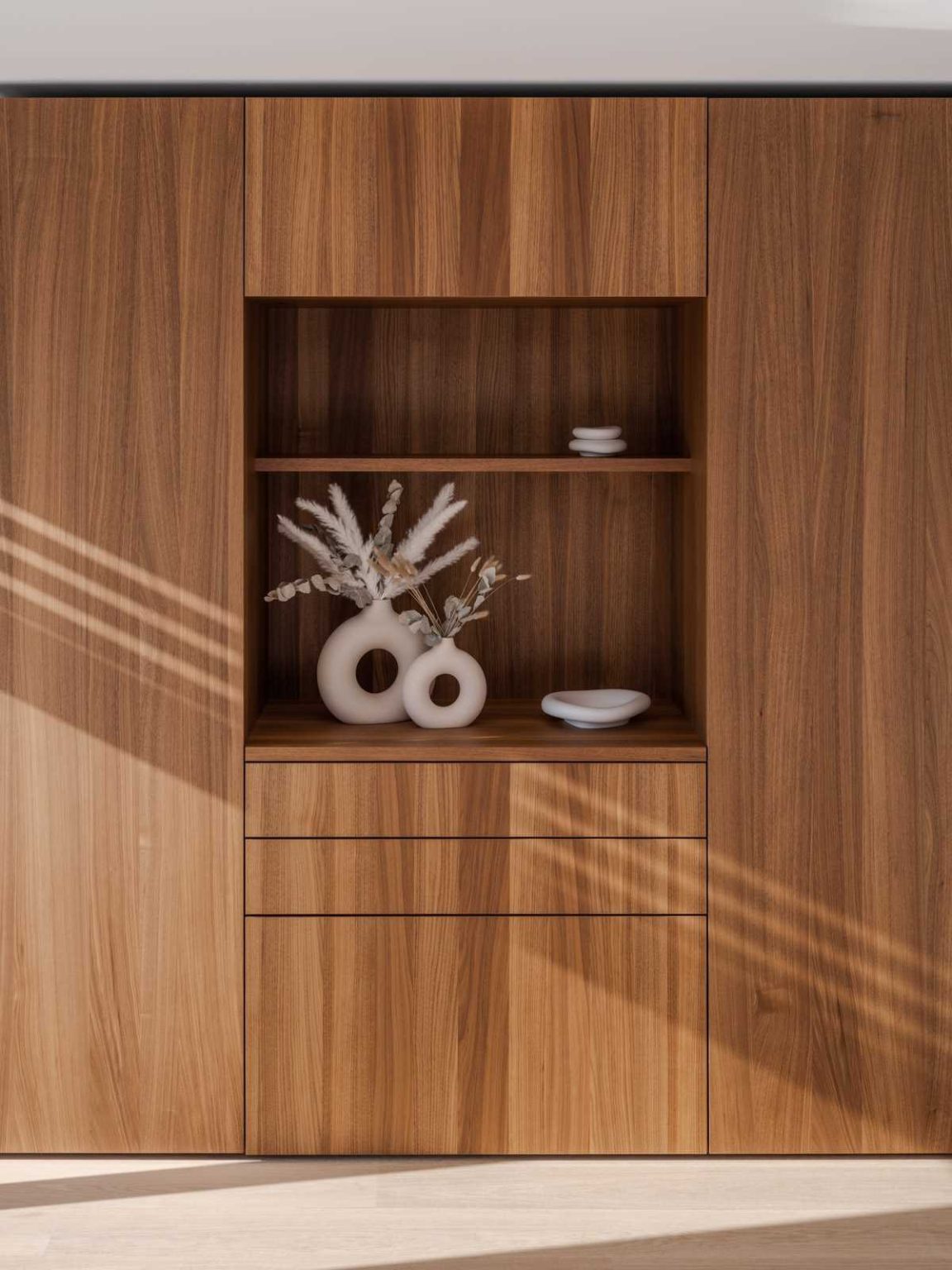Warm wood cabinetry, hardwood floors and subtle hidden lighting create a cosy, modern primary bedroom in this Lausen, Switzerland home renovation.