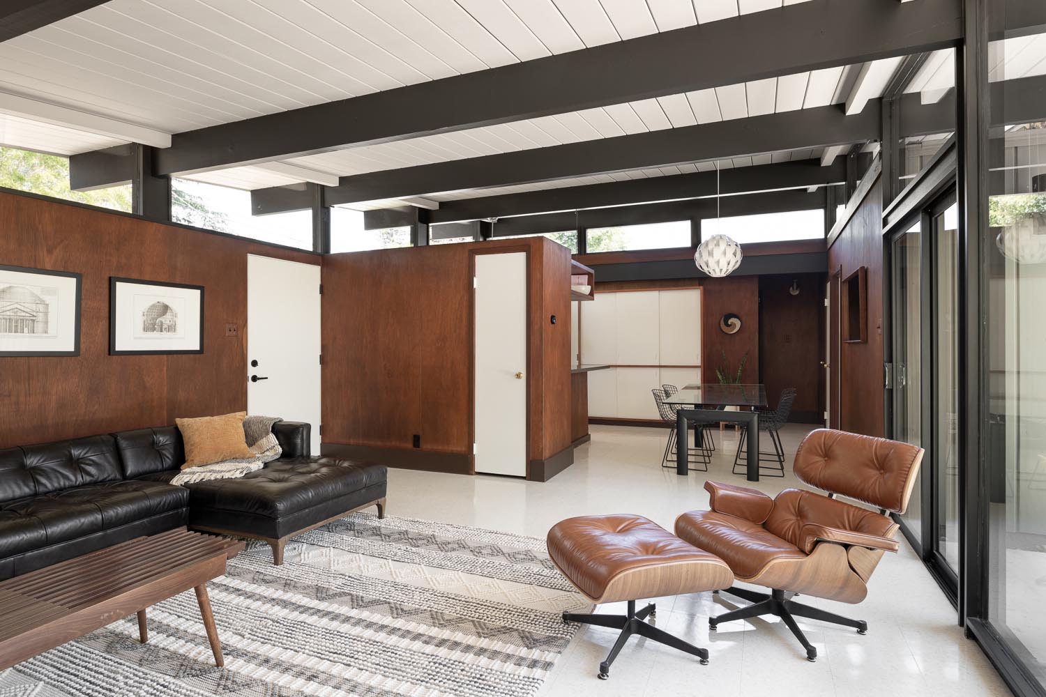 Take a look inside the renovated Eichler living room, where a bright white ceiling and dark structural elements create a fresh contrast with the home's mid-century architecture.