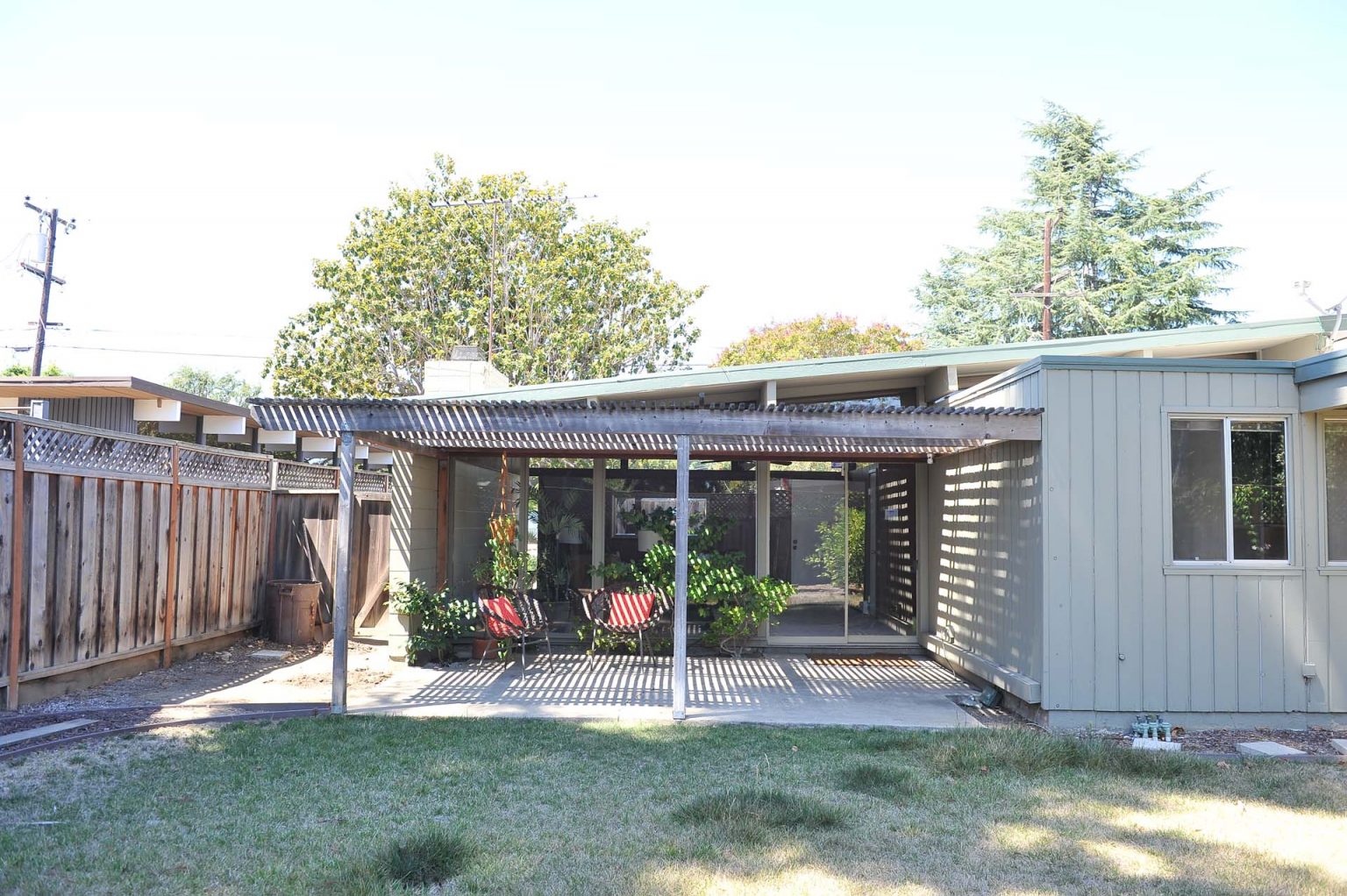 BEFORE - See how a light brown exterior, new grass and a modern patio transform the outdoor spaces of this Eichler house while opening the rear of the home to more morning light.