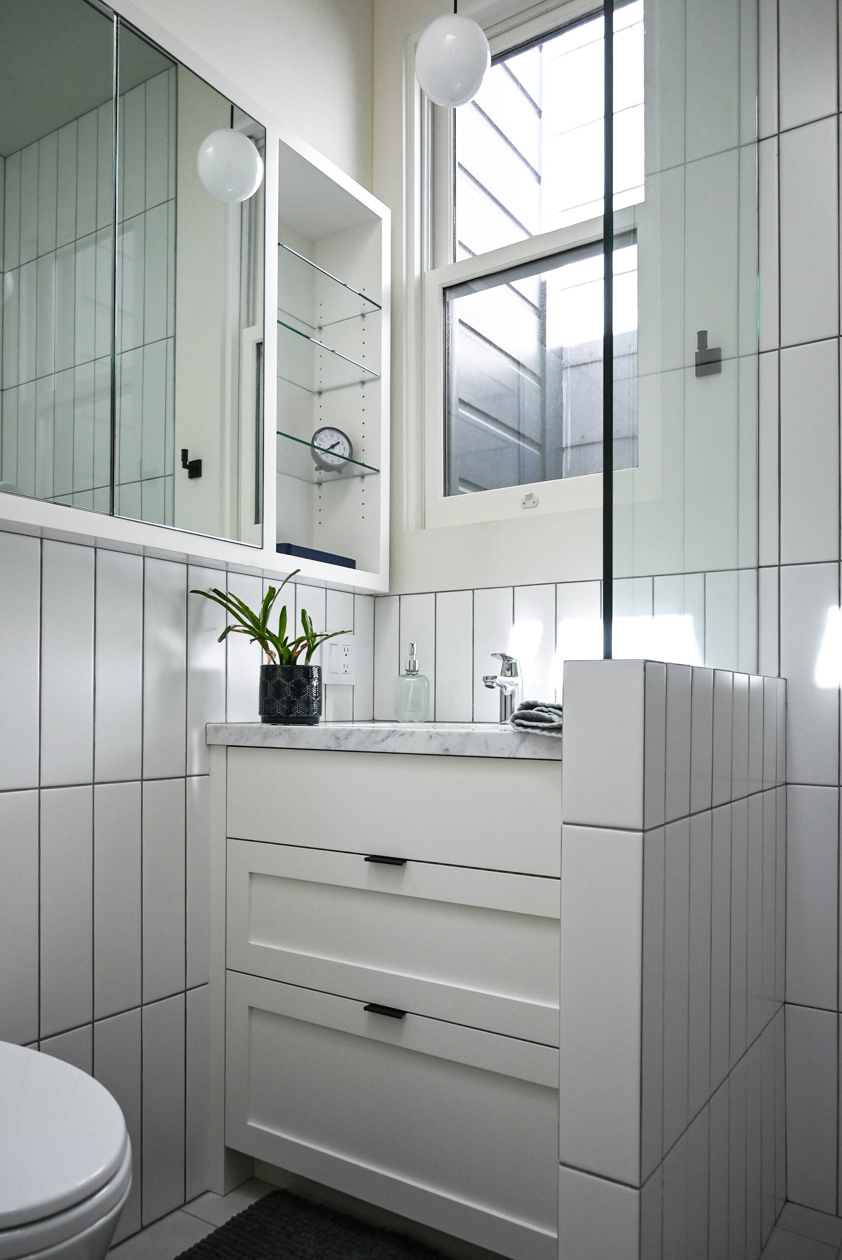 Inside the ADU, soft gray and white cabinetry, warm wood floors and large windows create a bright, comfortable kitchen, while the crisp white bathroom keeps the compact space clean and understated.