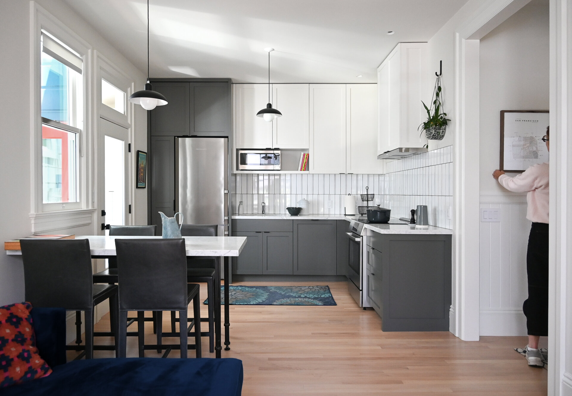 Inside the ADU, soft gray and white cabinetry, warm wood floors and large windows create a bright, comfortable kitchen, while the crisp white bathroom keeps the compact space clean and understated.