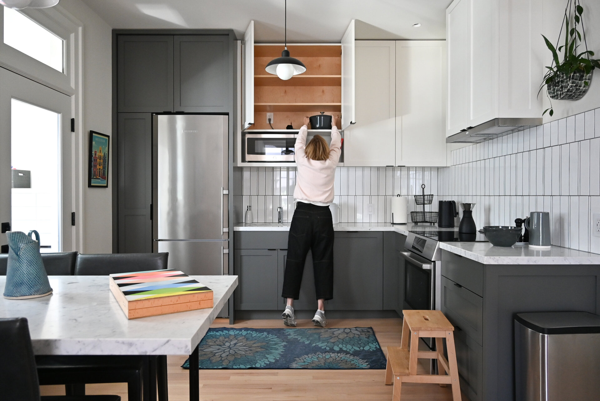Inside the ADU, soft gray and white cabinetry, warm wood floors and large windows create a bright, comfortable kitchen, while the crisp white bathroom keeps the compact space clean and understated.