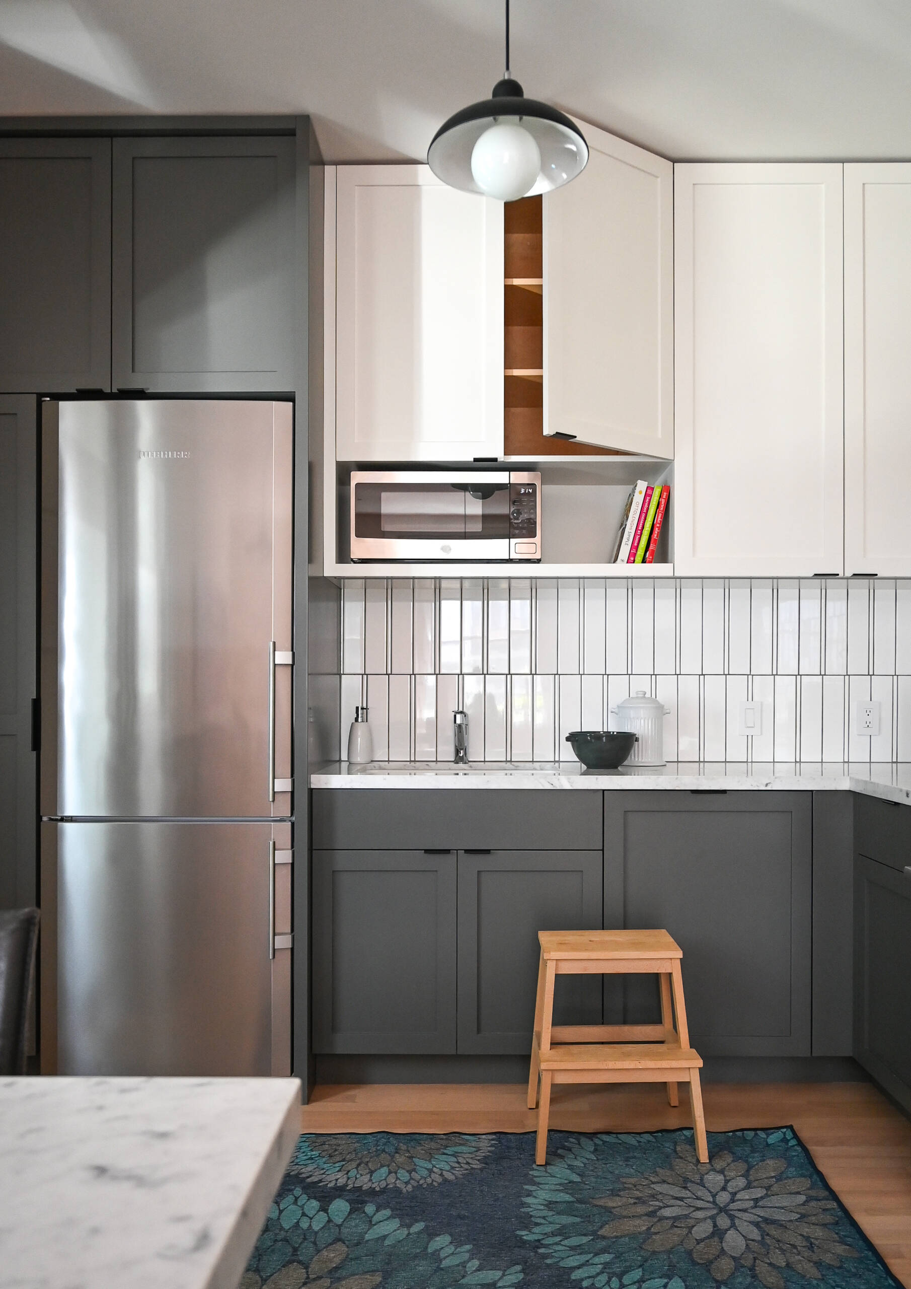 Inside the ADU, soft gray and white cabinetry, warm wood floors and large windows create a bright, comfortable kitchen, while the crisp white bathroom keeps the compact space clean and understated.