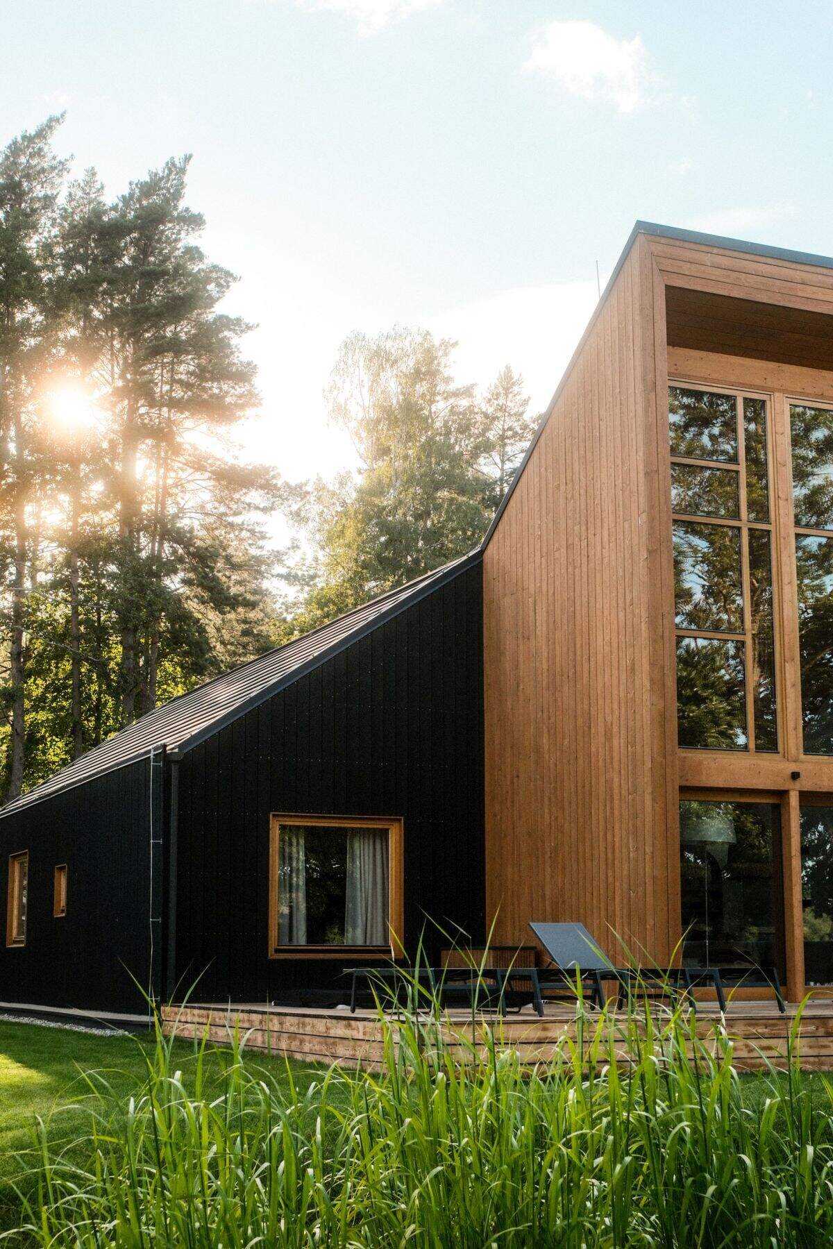 Explore the contemporary architecture of Kalbornia Mazury, featuring light wooden facades, dark private volumes and expansive glazing that opens the homes towards the Polish lake and forest.