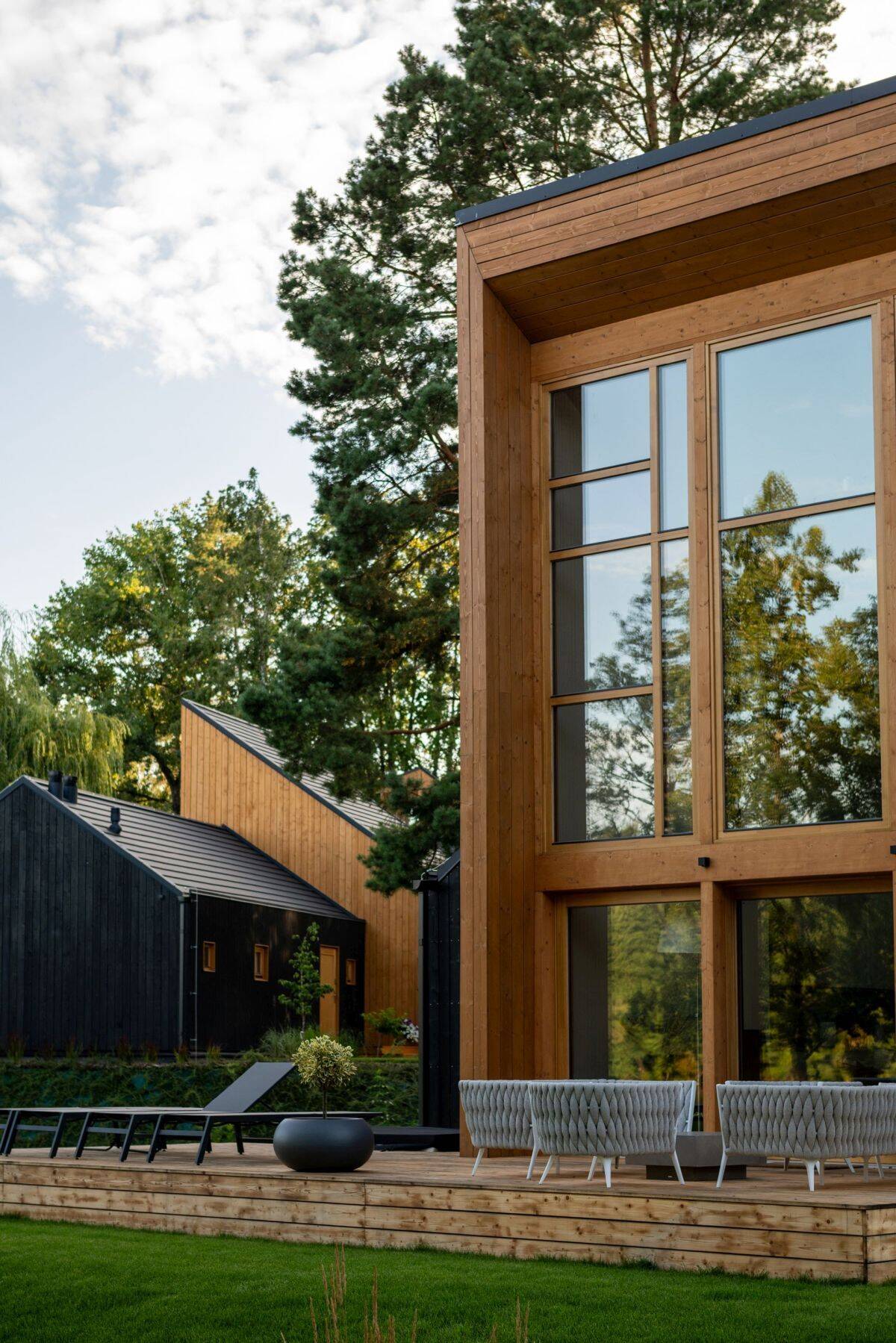 Explore the contemporary architecture of Kalbornia Mazury, featuring light wooden facades, dark private volumes and expansive glazing that opens the homes towards the Polish lake and forest.