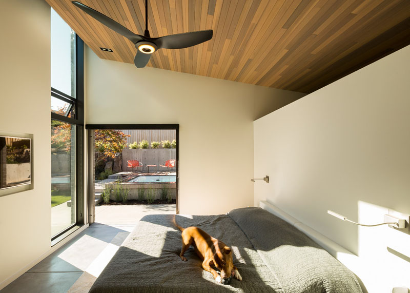 A sloped cedar ceiling and wide pocket door connecting directly to the backyard give the primary bedroom in this Bellevue home a strong indoor-outdoor connection.