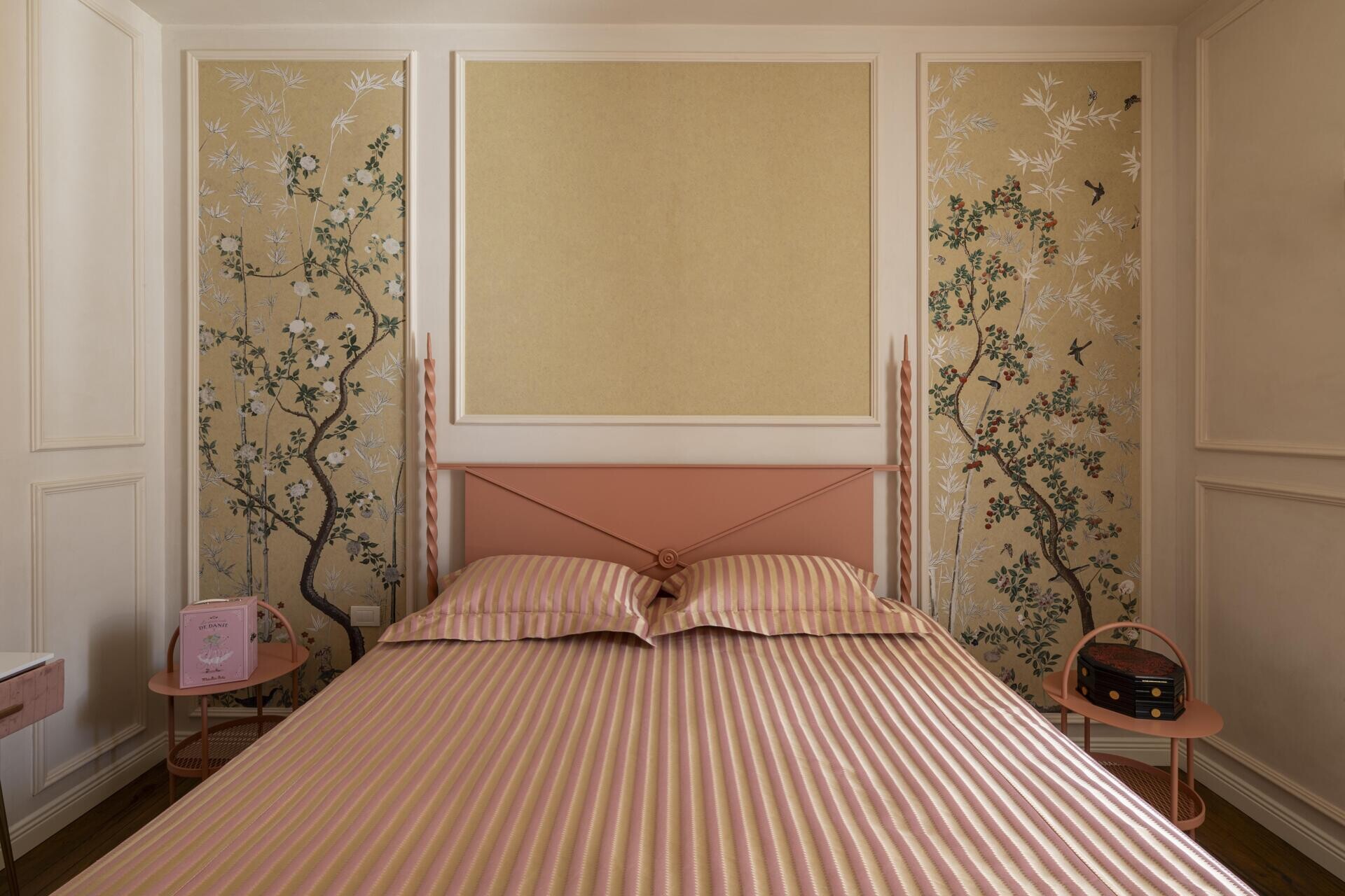 The girl's bedroom introduces the softer side of the palette, with salmon pink tones and delicate arboreal motifs on the decorated panels flanking the canopy bed.