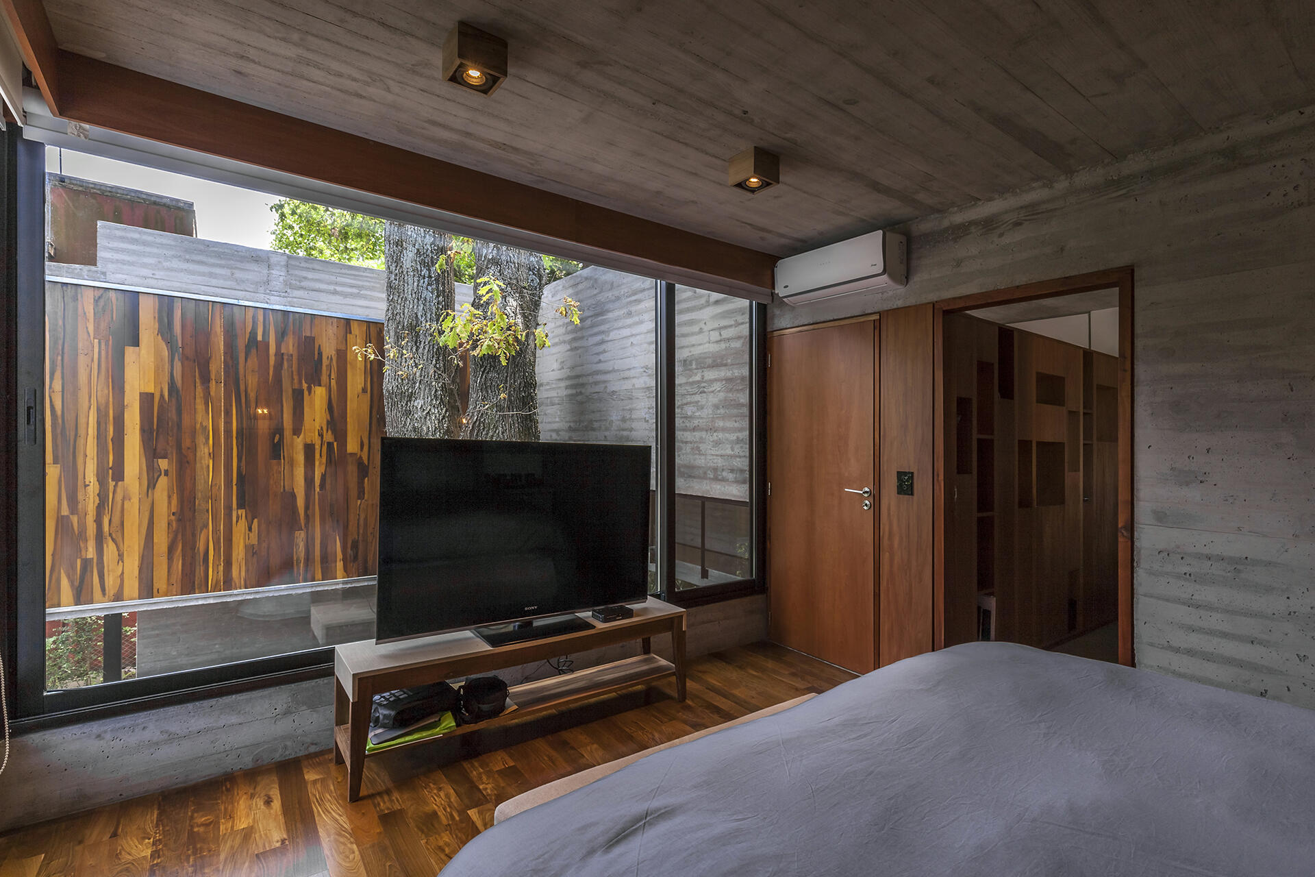 Large bedroom windows fill Casa Aranzazu with natural light while framing views of the mature trees surrounding the house.