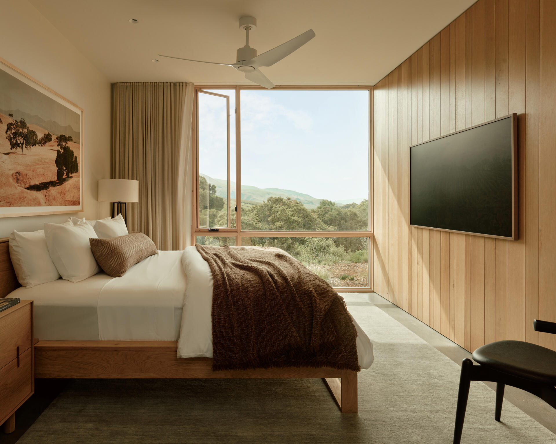 The guest bedroom at this California vineyard home continues the residence’s warm material palette of oak, plaster and custom millwork while benefiting from daylight and natural ventilation.