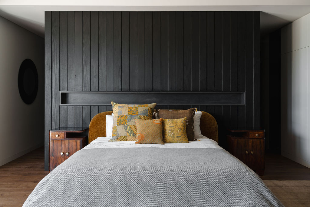 Dark timber paneling, warm wood floors and coastal views come together in the bedroom of Mezzanine House, a contemporary family home in Perth by Craig Steere Architects.