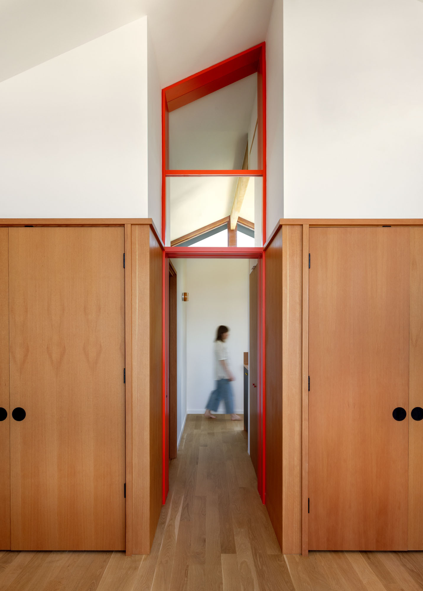 Tour the primary bedroom at Alki Lookout, where SHED paired existing panoramic Puget Sound windows with pale timber built-ins, a custom bed platform, concealed drawers and a pink-cushioned window bench.