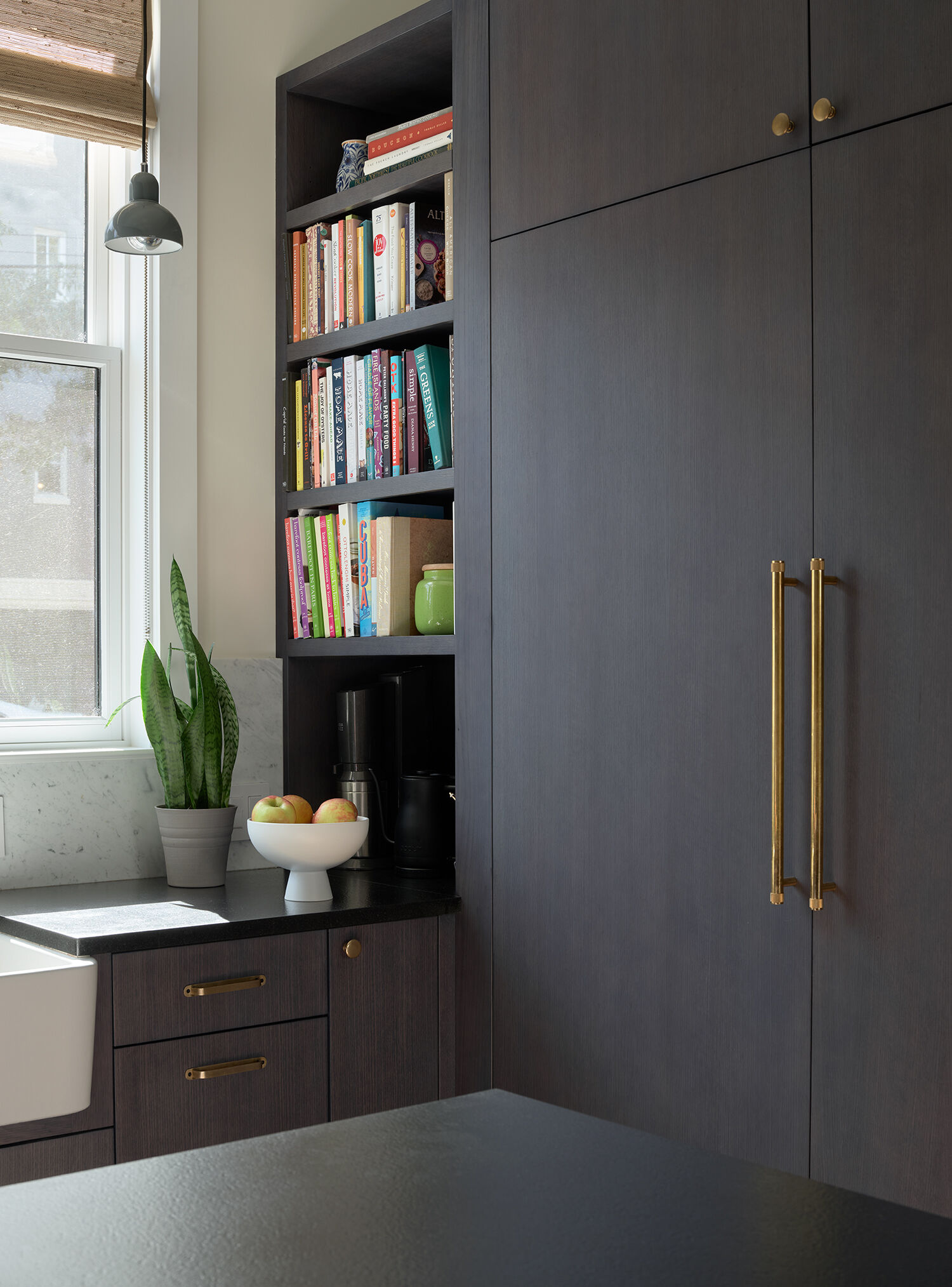 A warm San Francisco kitchen by Studio BBA features wood cabinetry, brass hardware, natural stone and a wide island designed for cooking, conversation and homework.