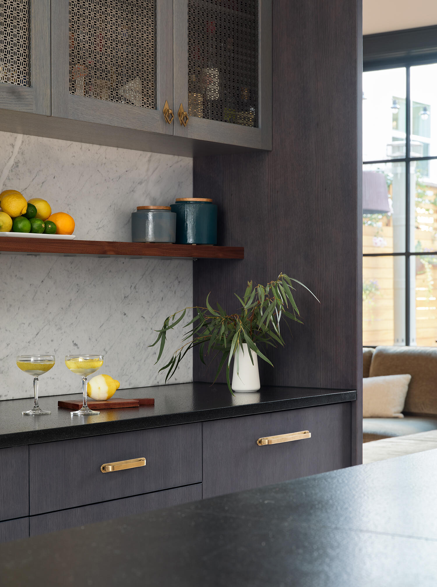 A warm San Francisco kitchen by Studio BBA features wood cabinetry, brass hardware, natural stone and a wide island designed for cooking, conversation and homework.