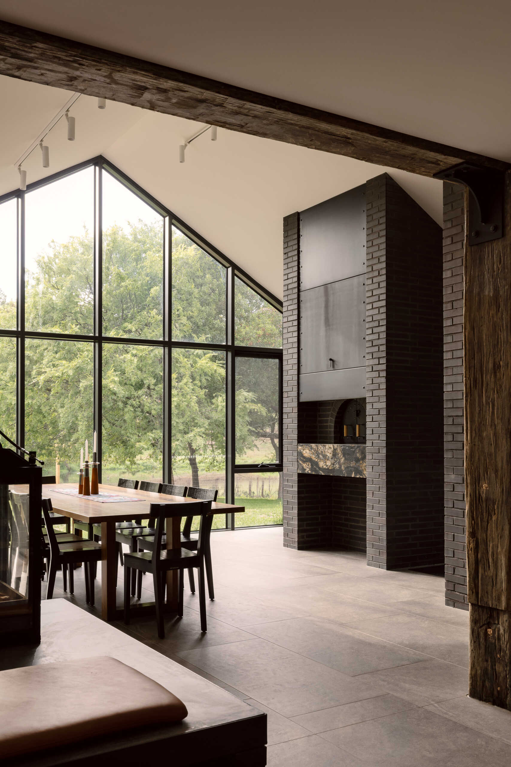 Explore the dining room at Yarra Valley House, where a large timber table, dark brick pizza oven and floor-to-ceiling windows overlook the lush Victorian landscape.