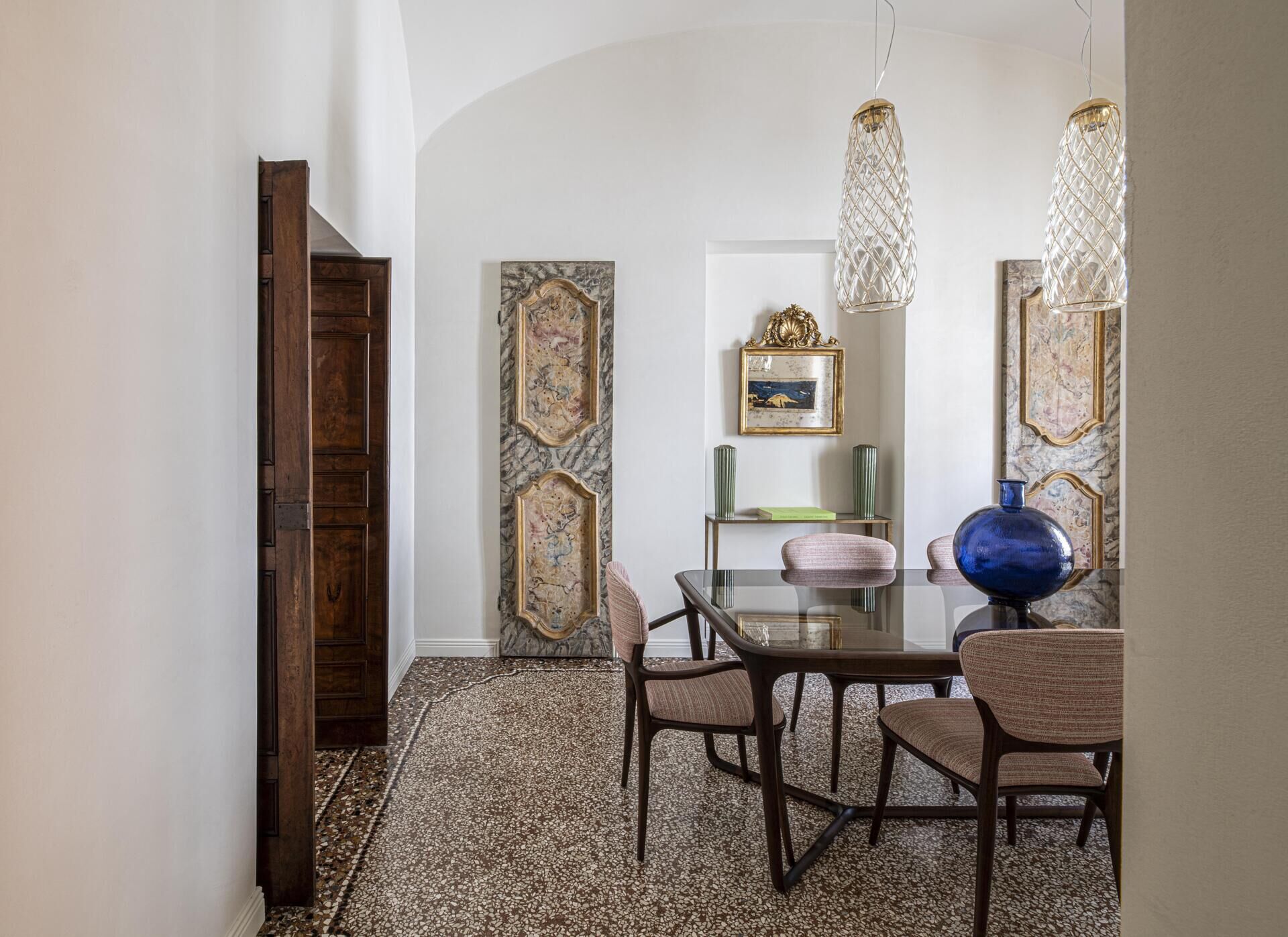 An elegant Italian dining room combines antique wardrobe panels with delicate woven chandeliers, gold details and contemporary dining furniture.