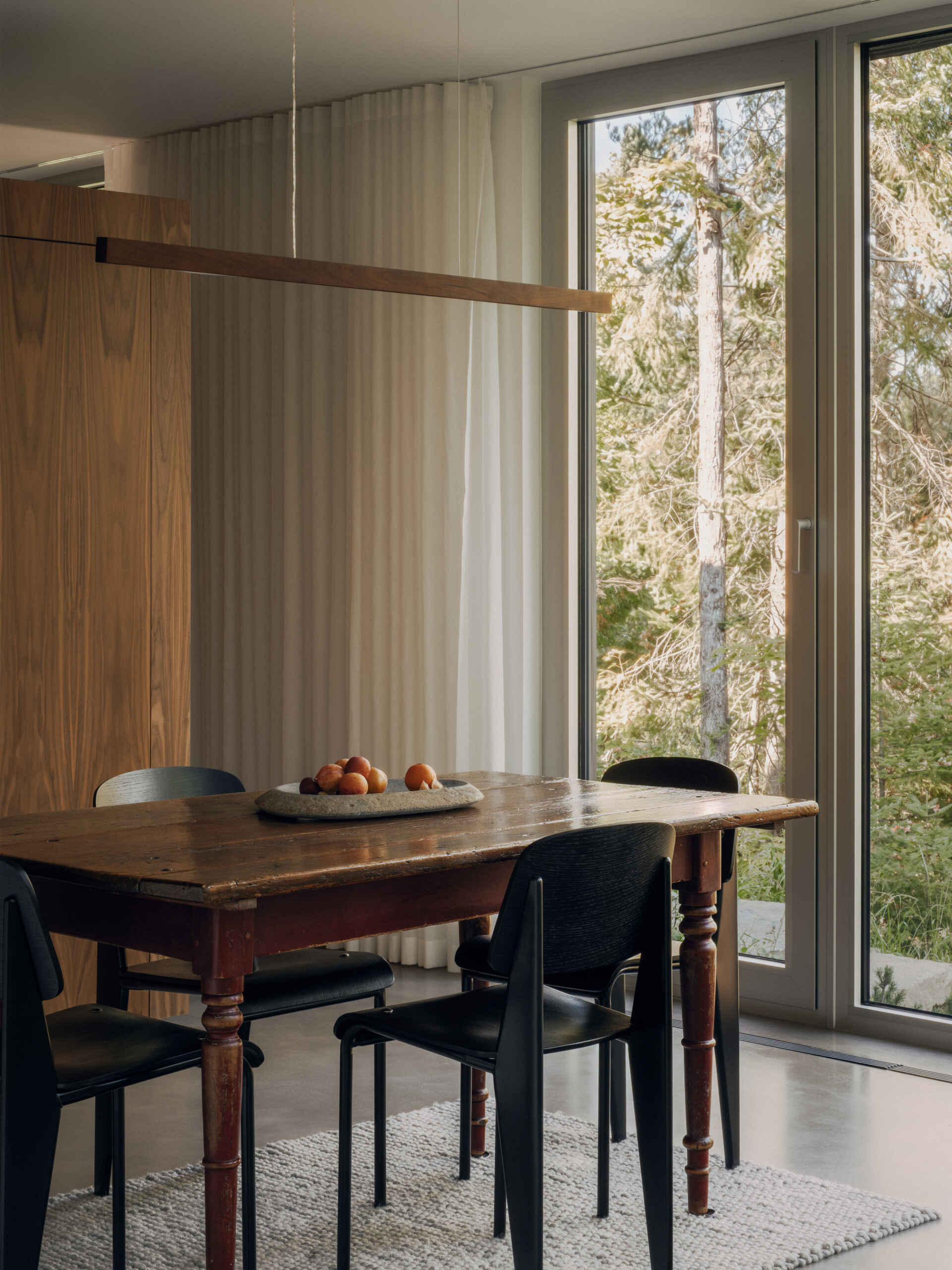 See how the dining room and kitchen are arranged around open views of the lake and forest in this contemporary Laurentians chalet by Appareil Architecture.