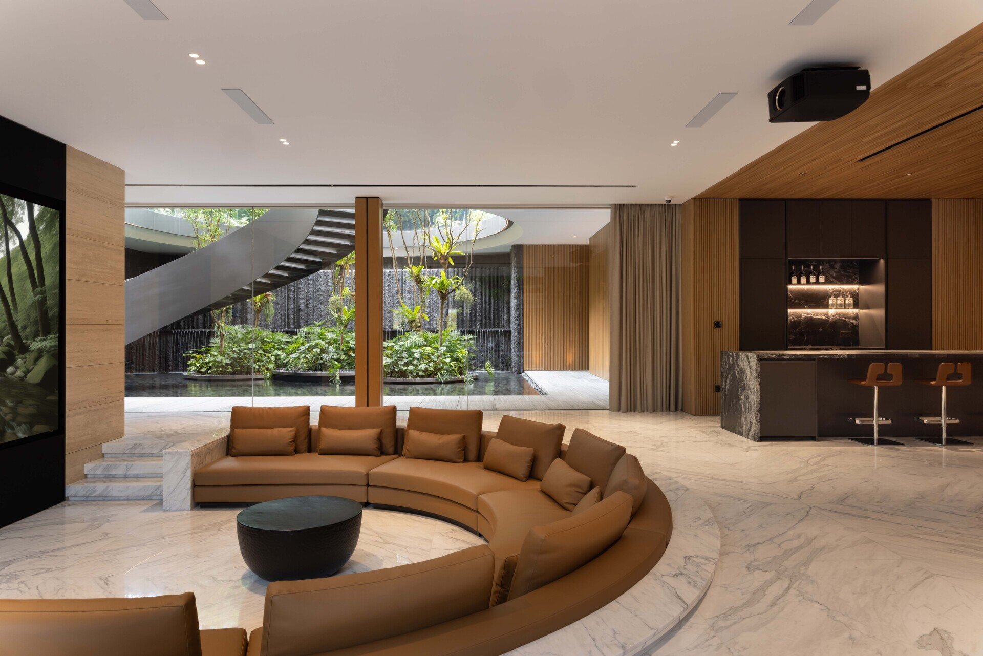 A sunken entertainment room with a wine cellar sits between two water gardens, with cascading water and trees visible through glass.