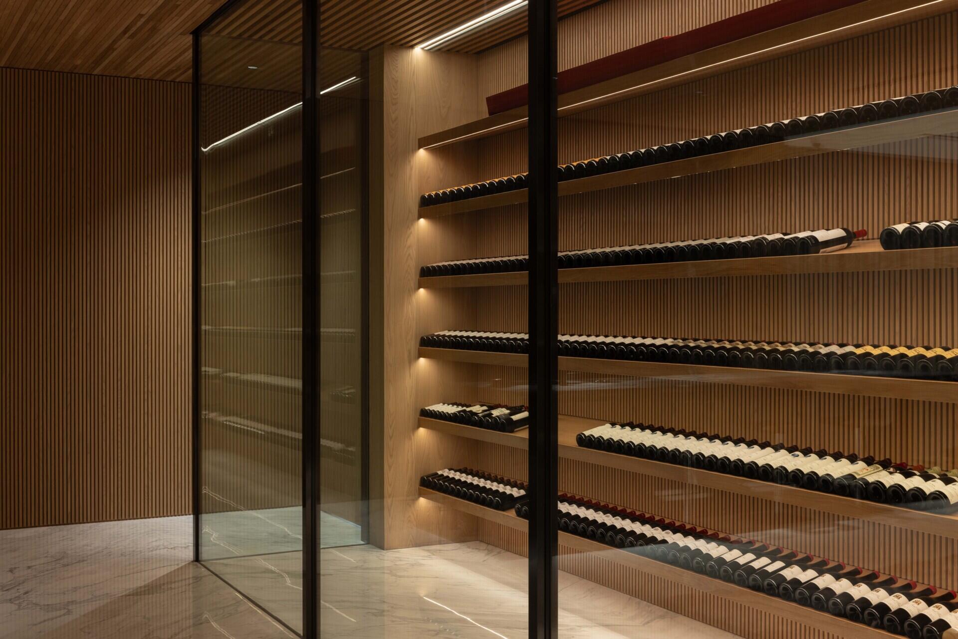 A sunken entertainment room with a wine cellar sits between two water gardens, with cascading water and trees visible through glass.