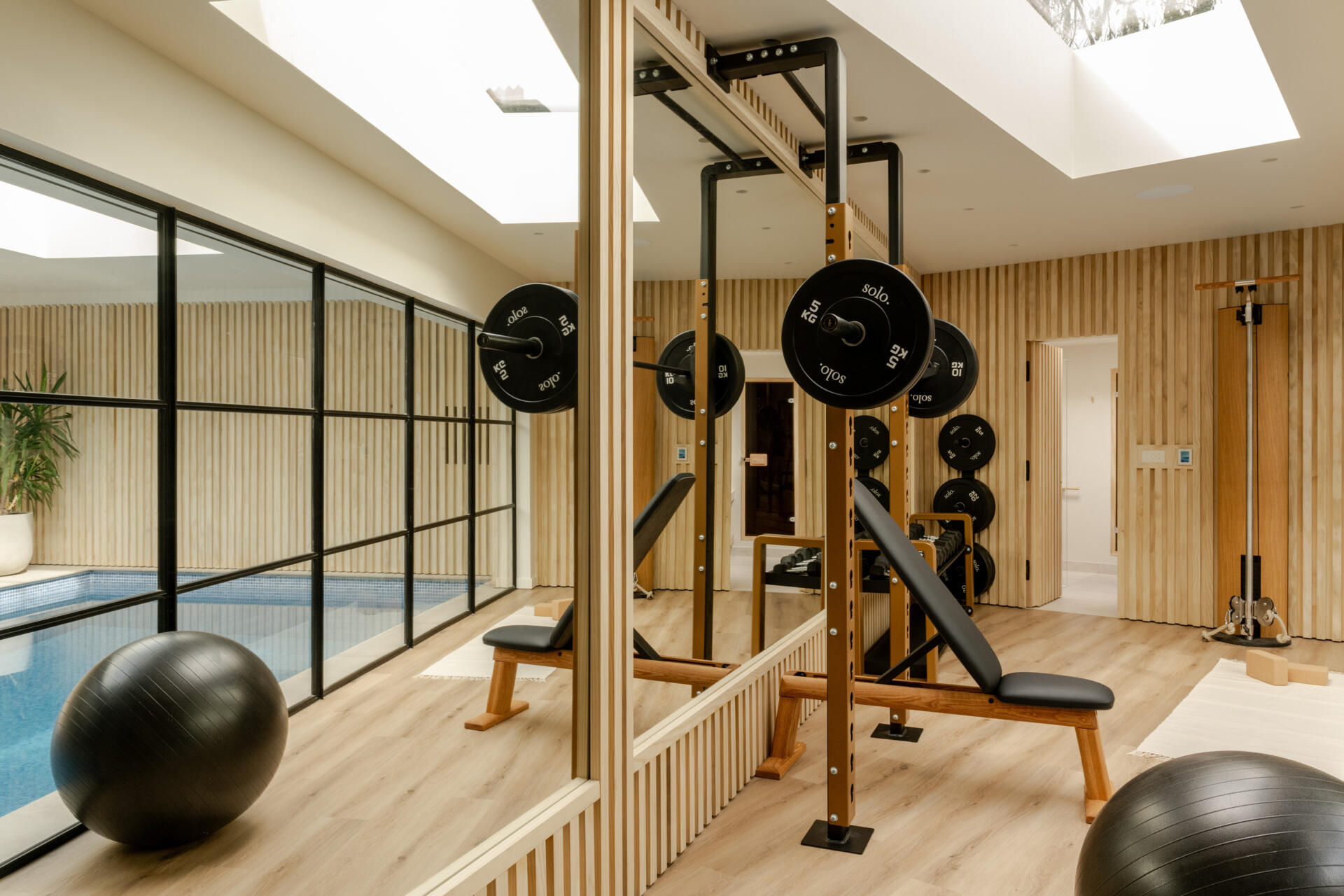 Take a look at the home gym, indoor pool and wood-lined sauna at Thirsk Cottage, combining warm timber, black equipment, skylights and glass walls.