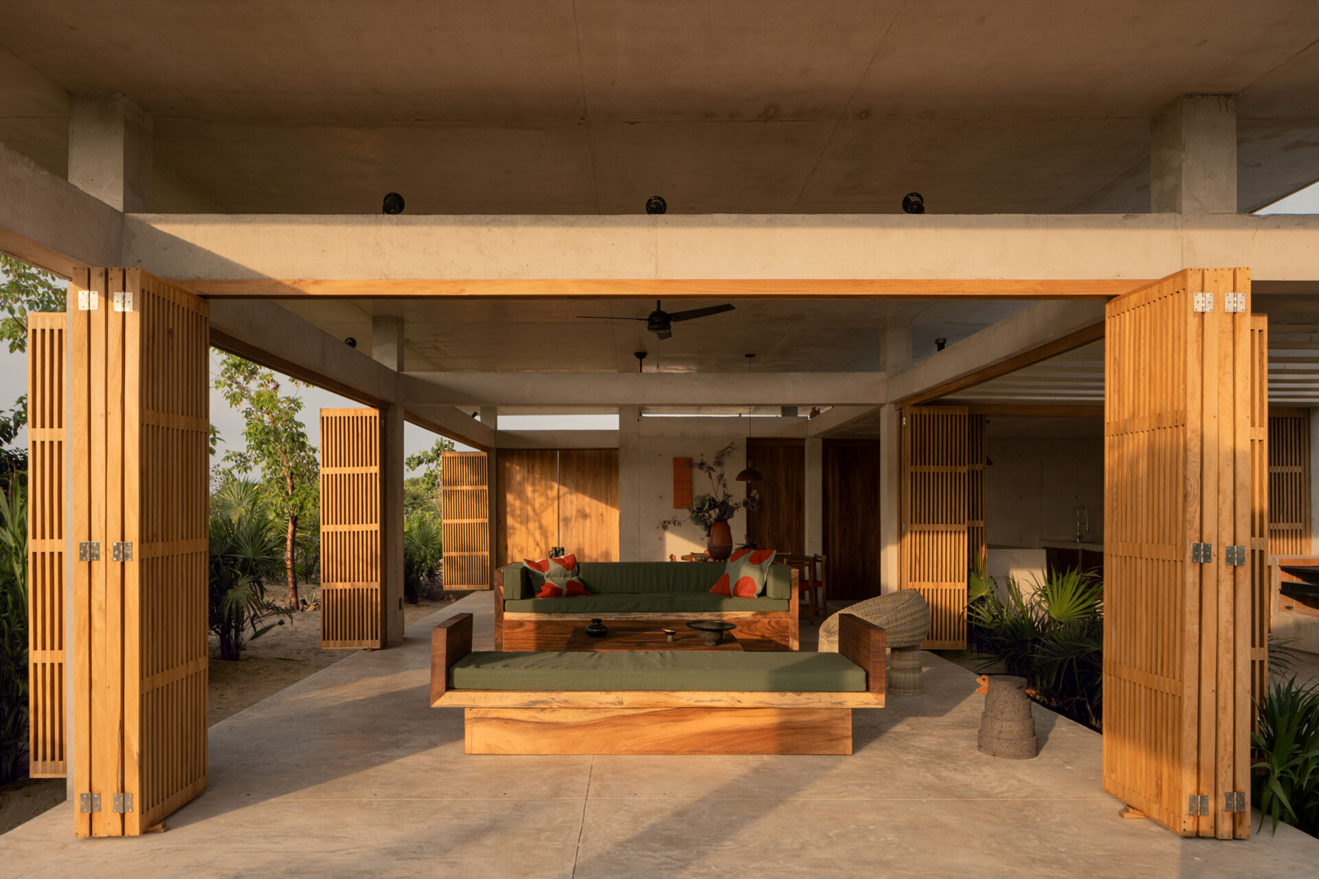The interiors of Casa Cieno combine exposed concrete with warm timber, woven textures, terracotta accents and large openings overlooking the surrounding landscape.