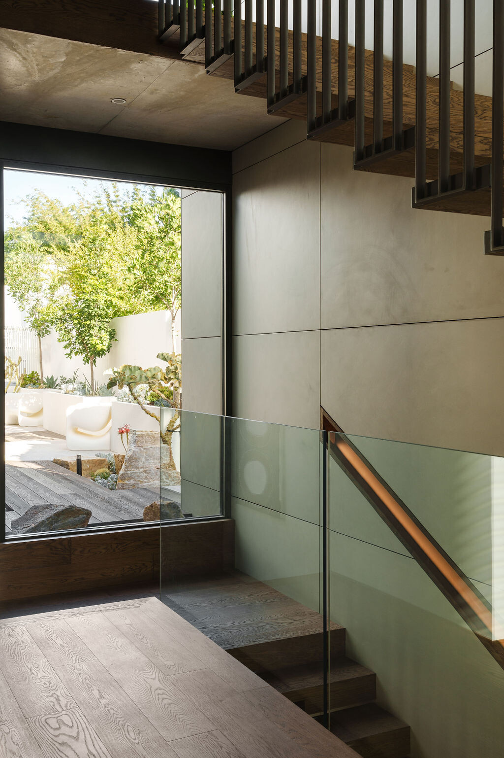 Mezzanine House features two distinctive staircases, combining floating timber treads, black metal, glass balustrades and natural light within the contemporary Perth home.