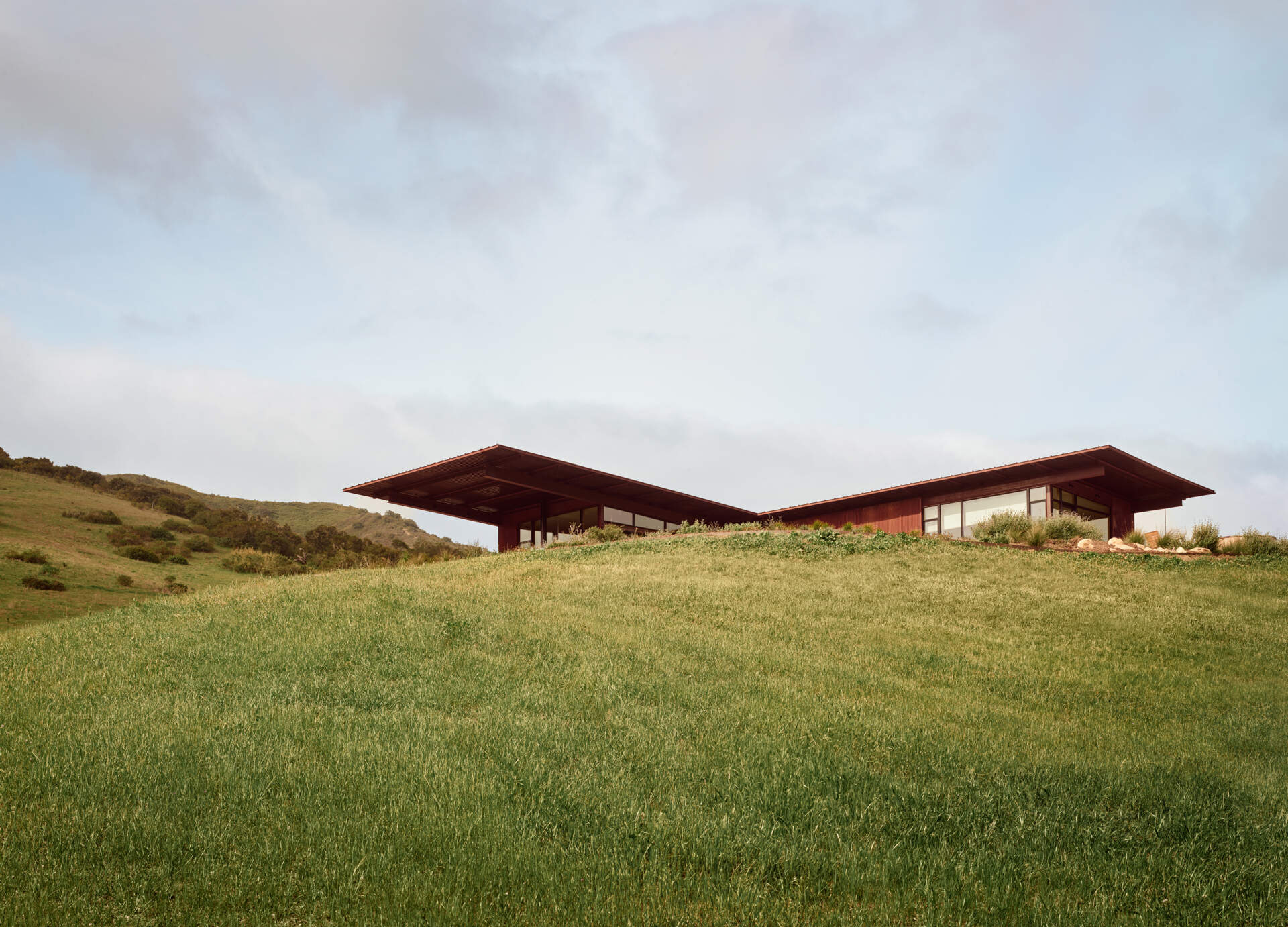 Explore the compact T-shaped plan of Vineyard Residence by Clayton Korte, with private bedroom suites surrounding a central kitchen and living area and outdoor spaces extending at both ends.