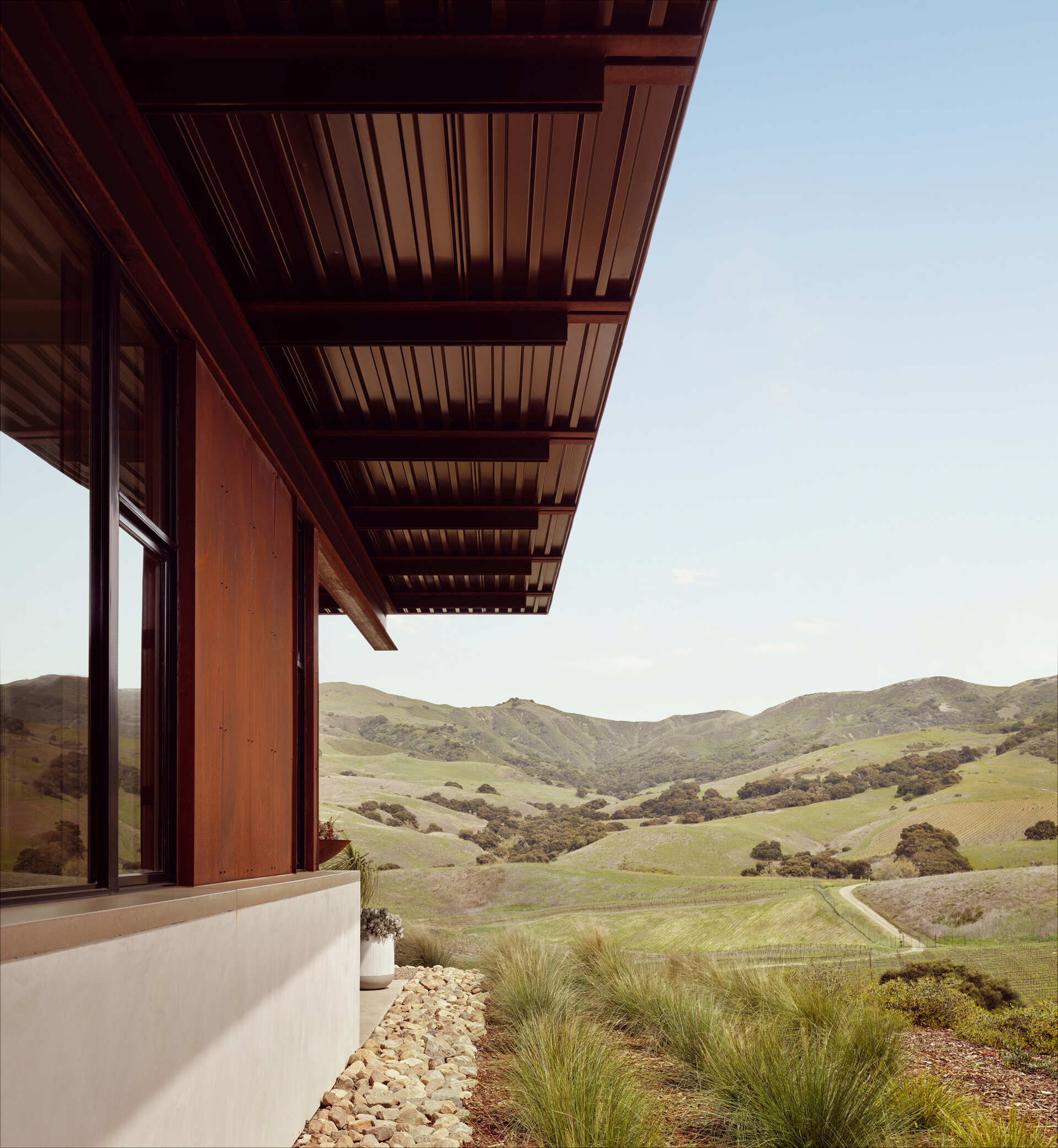 Weathering steel, stucco and a rainscreen give this California vineyard residence a warm, durable exterior inspired by the agricultural character of the surrounding area.