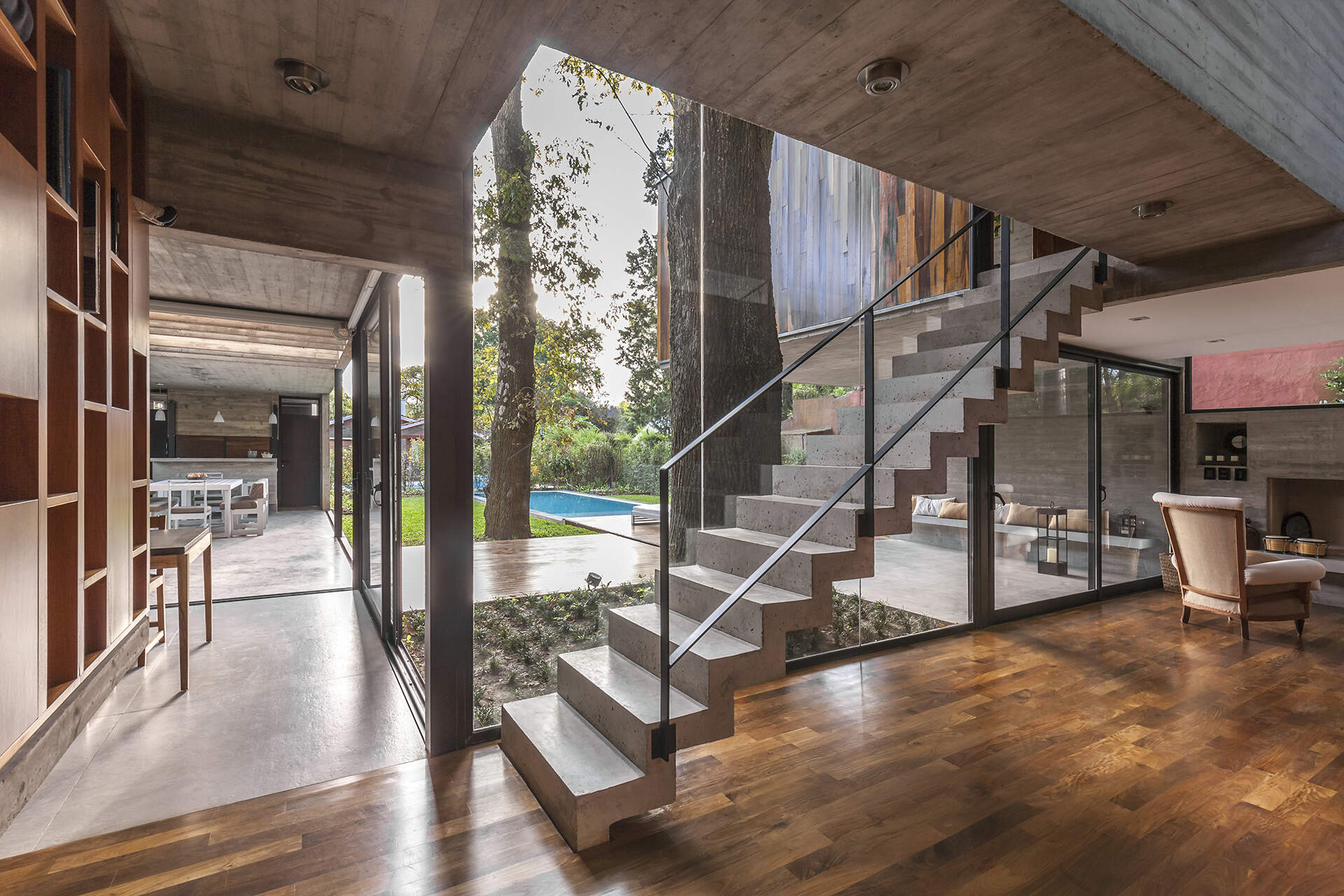 Concrete stairs and large windows create a strong architectural feature inside Casa Aranzazu, with the staircase also visible from the backyard.