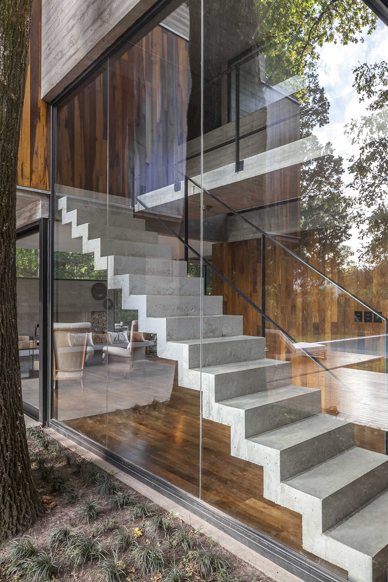 Concrete stairs and large windows create a strong architectural feature inside Casa Aranzazu, with the staircase also visible from the backyard.