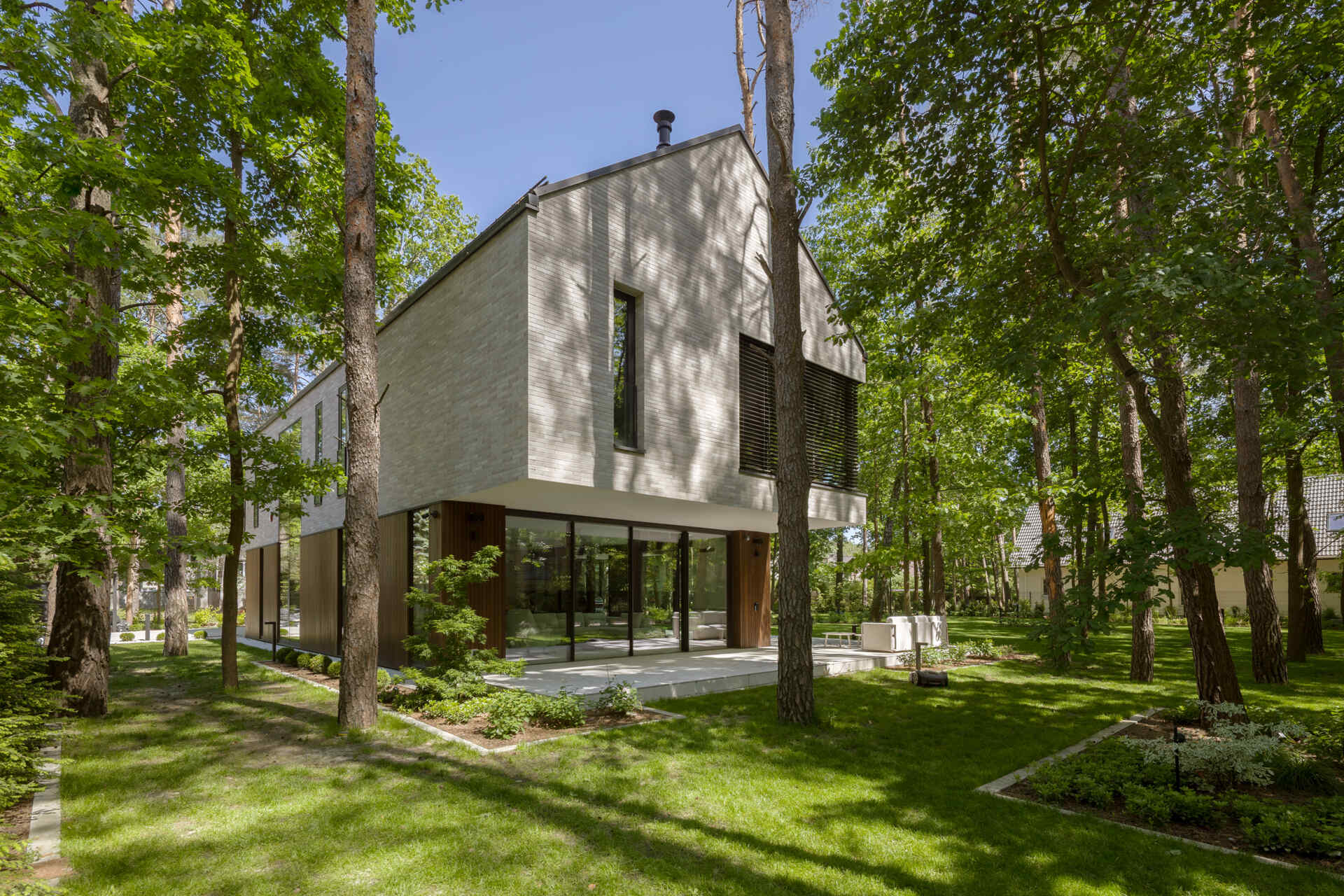 Two intersecting volumes give The Intersecting House near Warsaw its distinctive form. Designed by Exterio Architektura, the home combines pitched roofs, contrasting materials and a strong relationship with the surrounding pine forest.