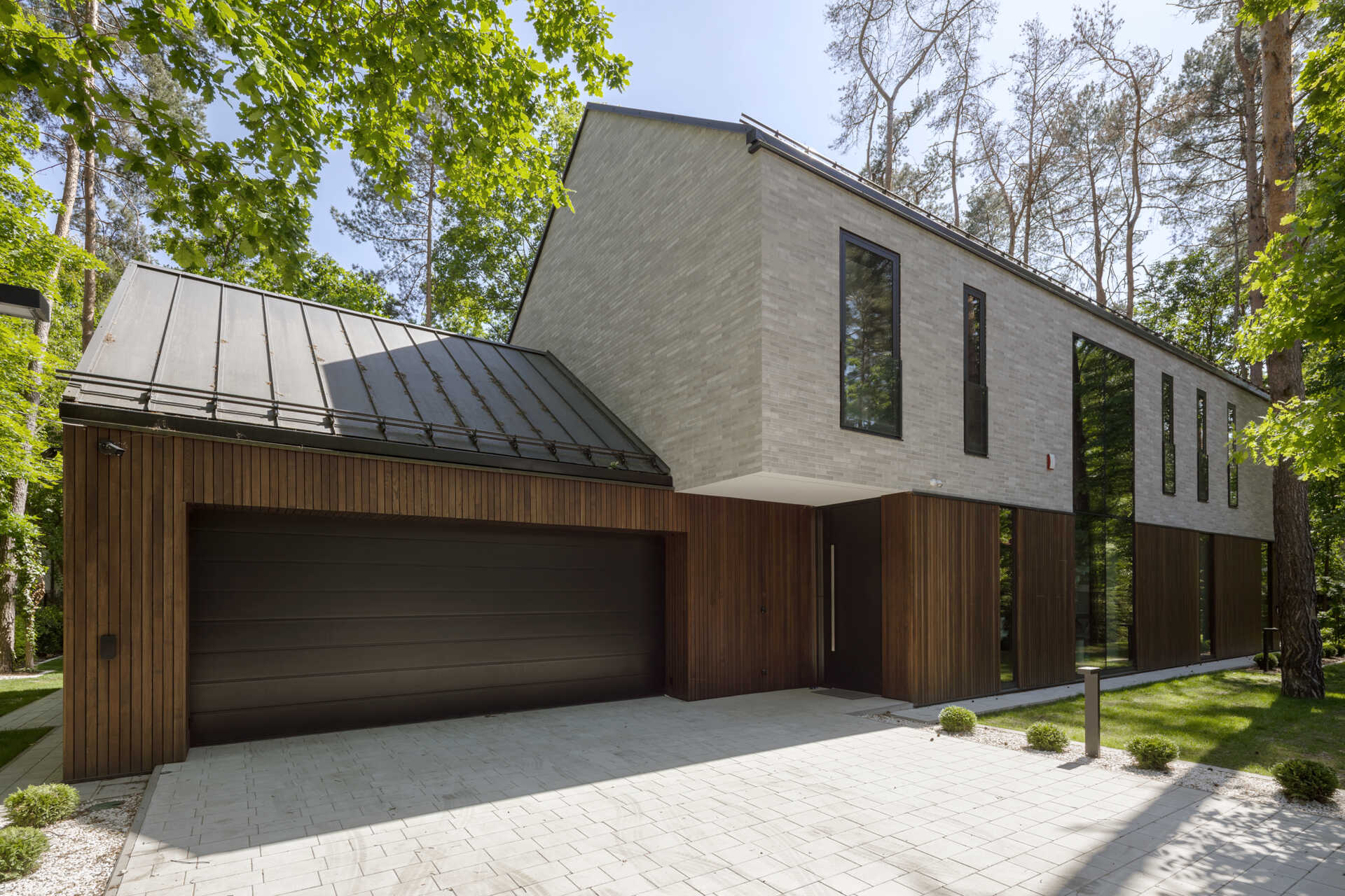 Two intersecting volumes give The Intersecting House near Warsaw its distinctive form. Designed by Exterio Architektura, the home combines pitched roofs, contrasting materials and a strong relationship with the surrounding pine forest.