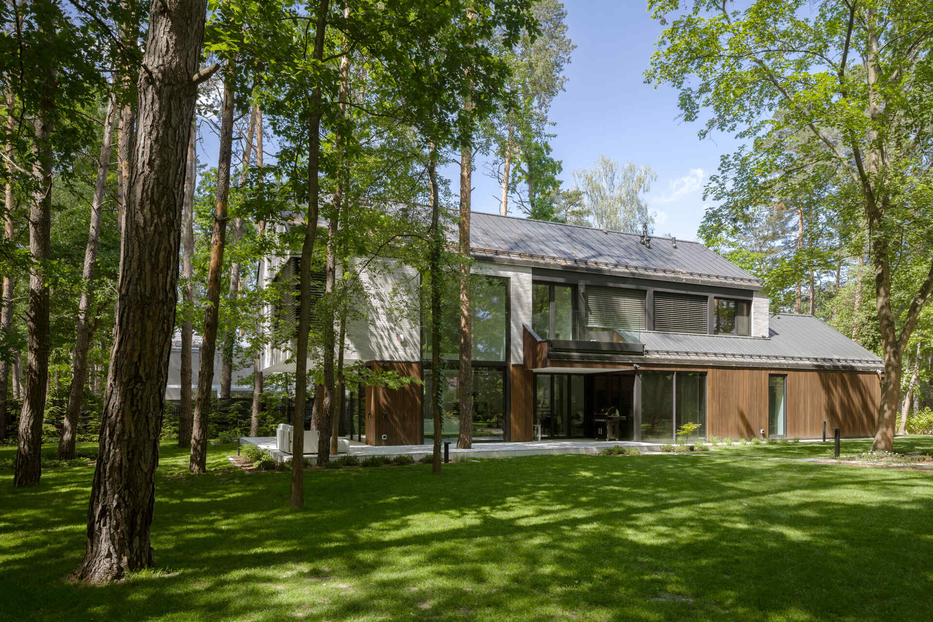 Two intersecting volumes give The Intersecting House near Warsaw its distinctive form. Designed by Exterio Architektura, the home combines pitched roofs, contrasting materials and a strong relationship with the surrounding pine forest.