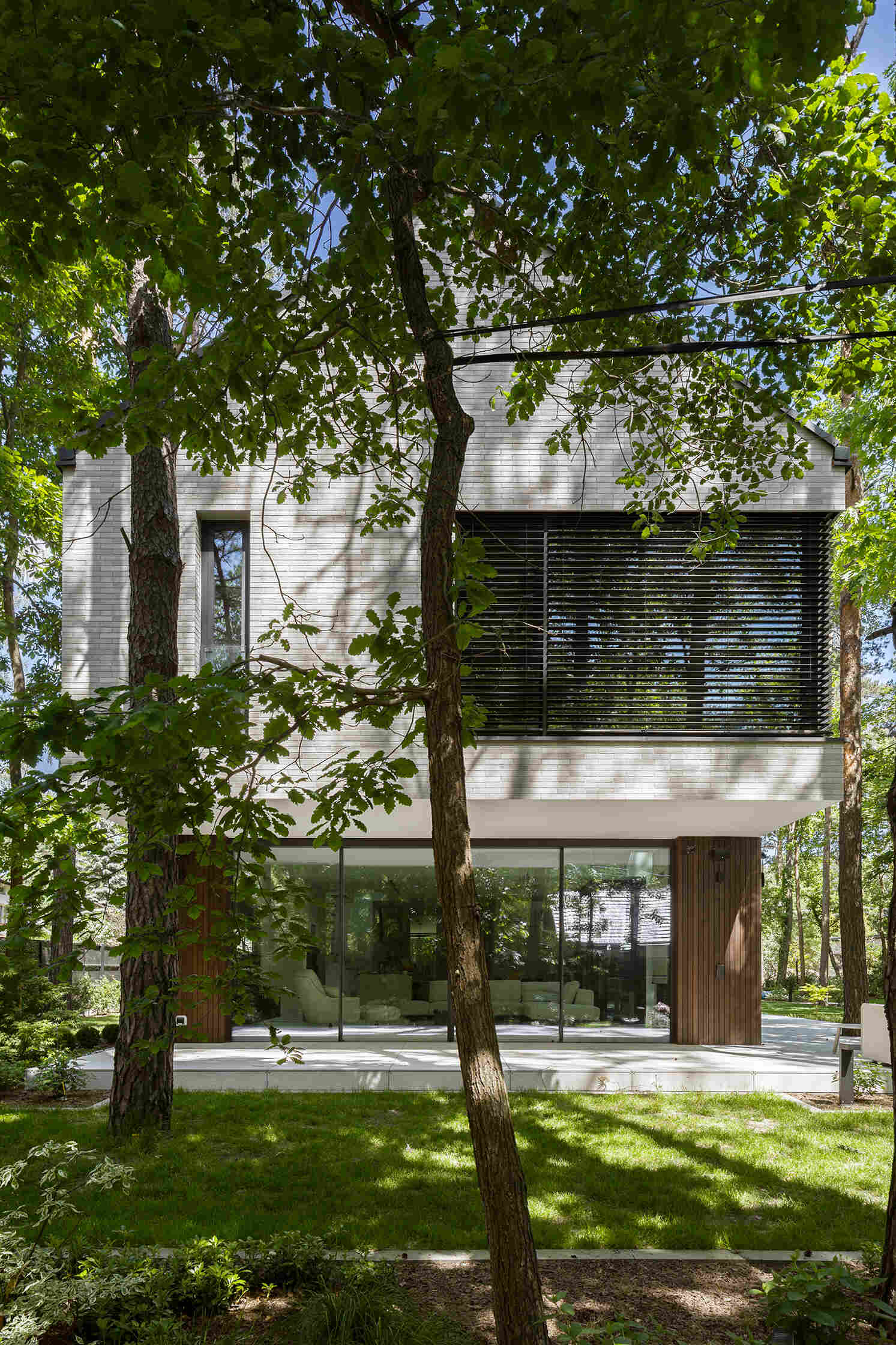 Two intersecting volumes give The Intersecting House near Warsaw its distinctive form. Designed by Exterio Architektura, the home combines pitched roofs, contrasting materials and a strong relationship with the surrounding pine forest.