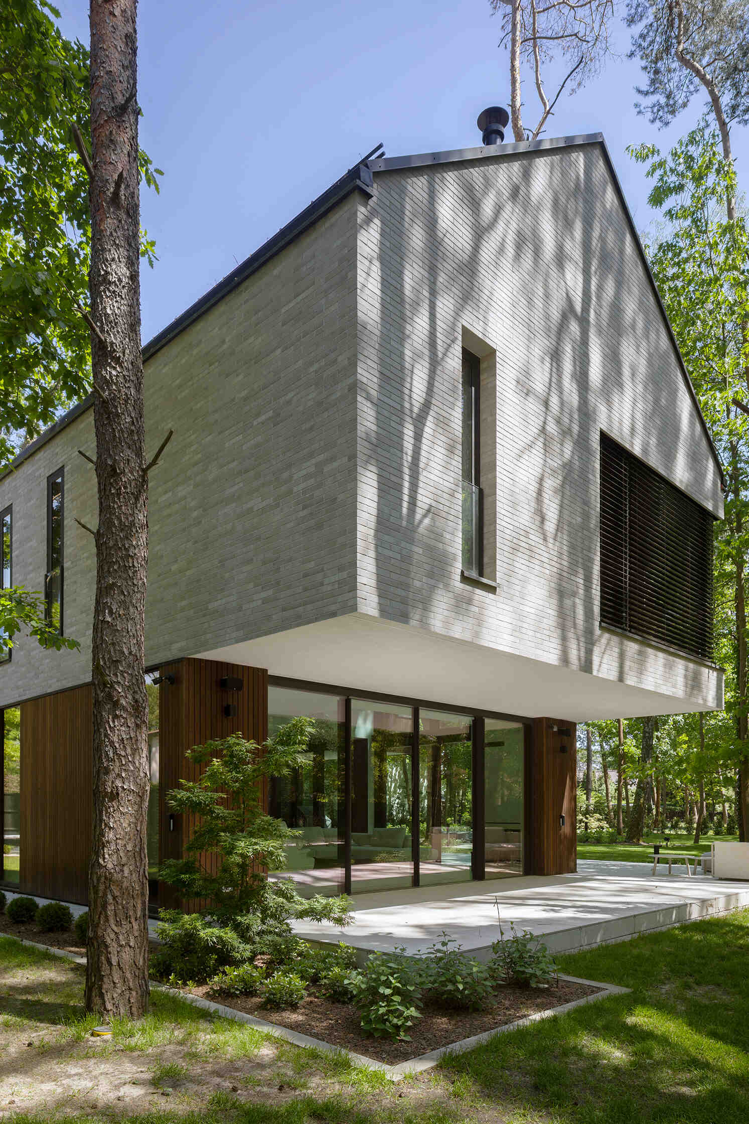 Two intersecting volumes give The Intersecting House near Warsaw its distinctive form. Designed by Exterio Architektura, the home combines pitched roofs, contrasting materials and a strong relationship with the surrounding pine forest.